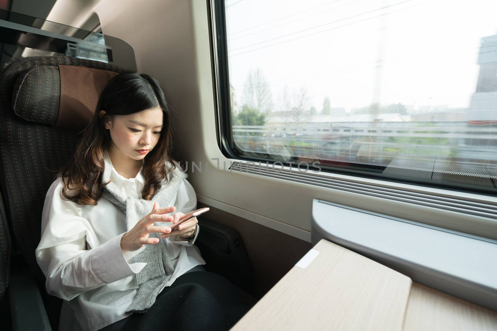 Beautiful asian girl using smartphone while travelling on the train, communication concept by beer5020