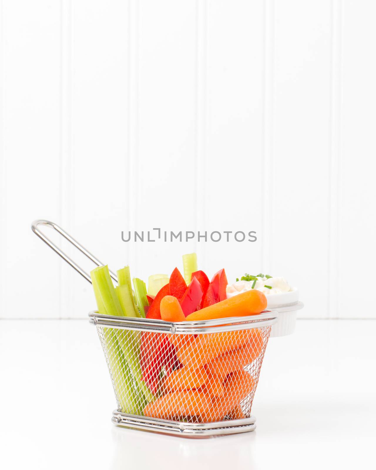Raw vegetables and dip in a fryer basket suggesting an alternative to greasy fried foods.