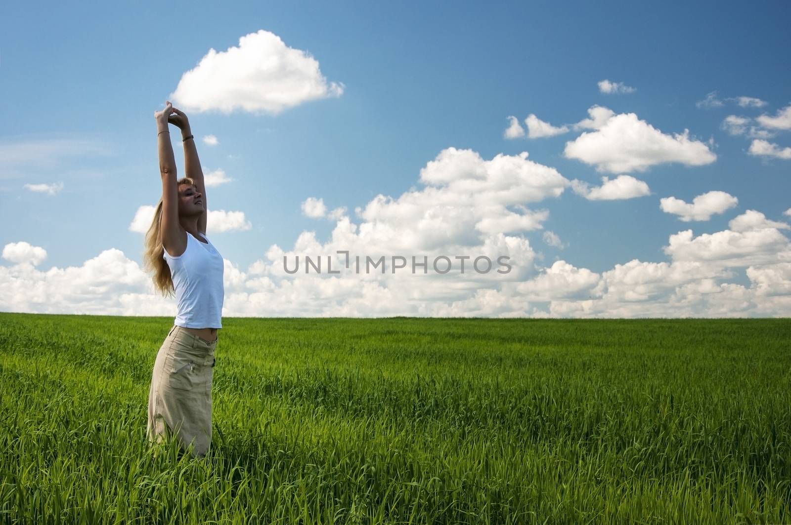 happy girl jumping in green wheat field at scenic rural background