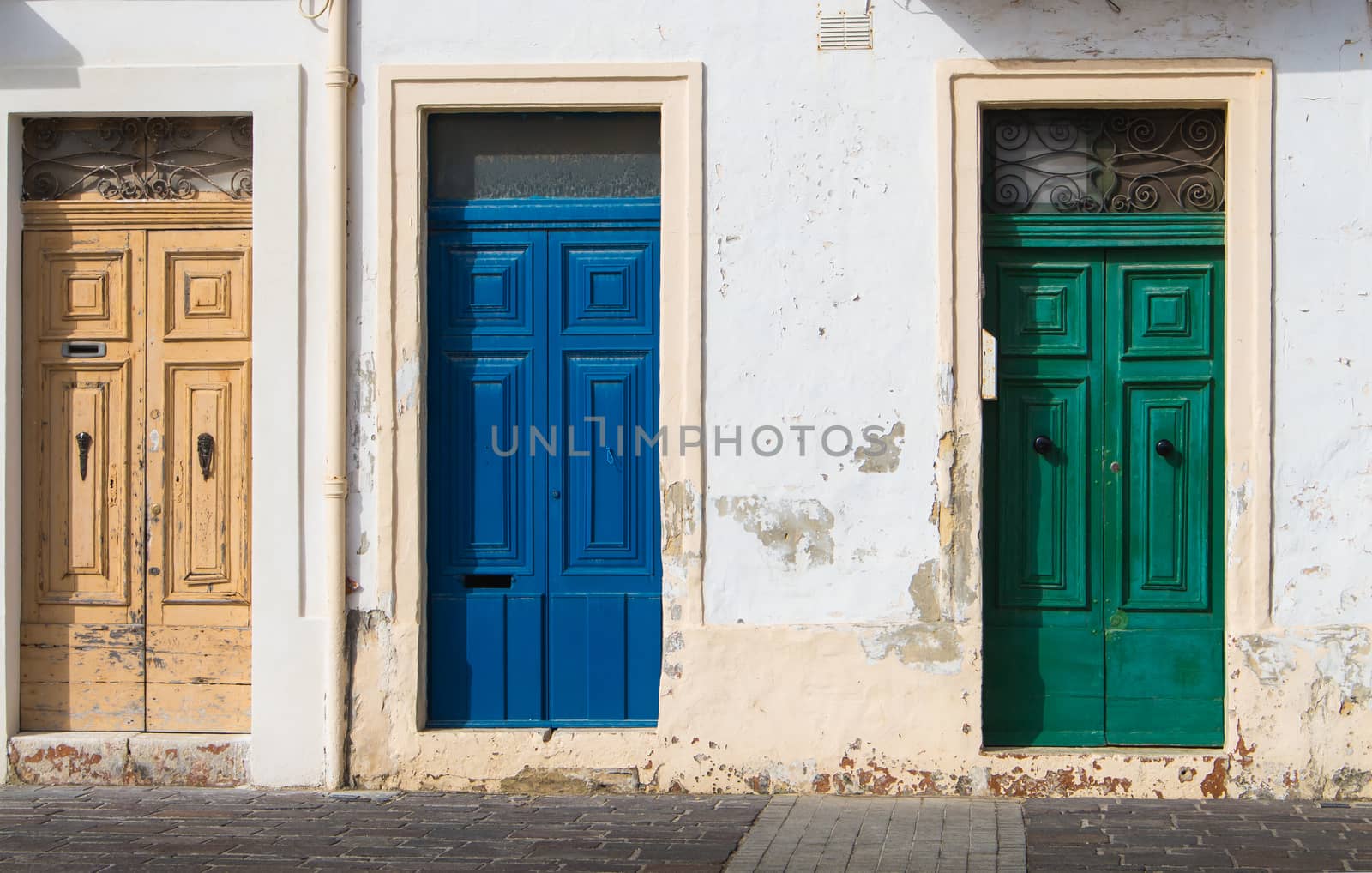 In the rays of morning sunlight, 3 similar doors, different in the color. House at the island Malta, Europe.