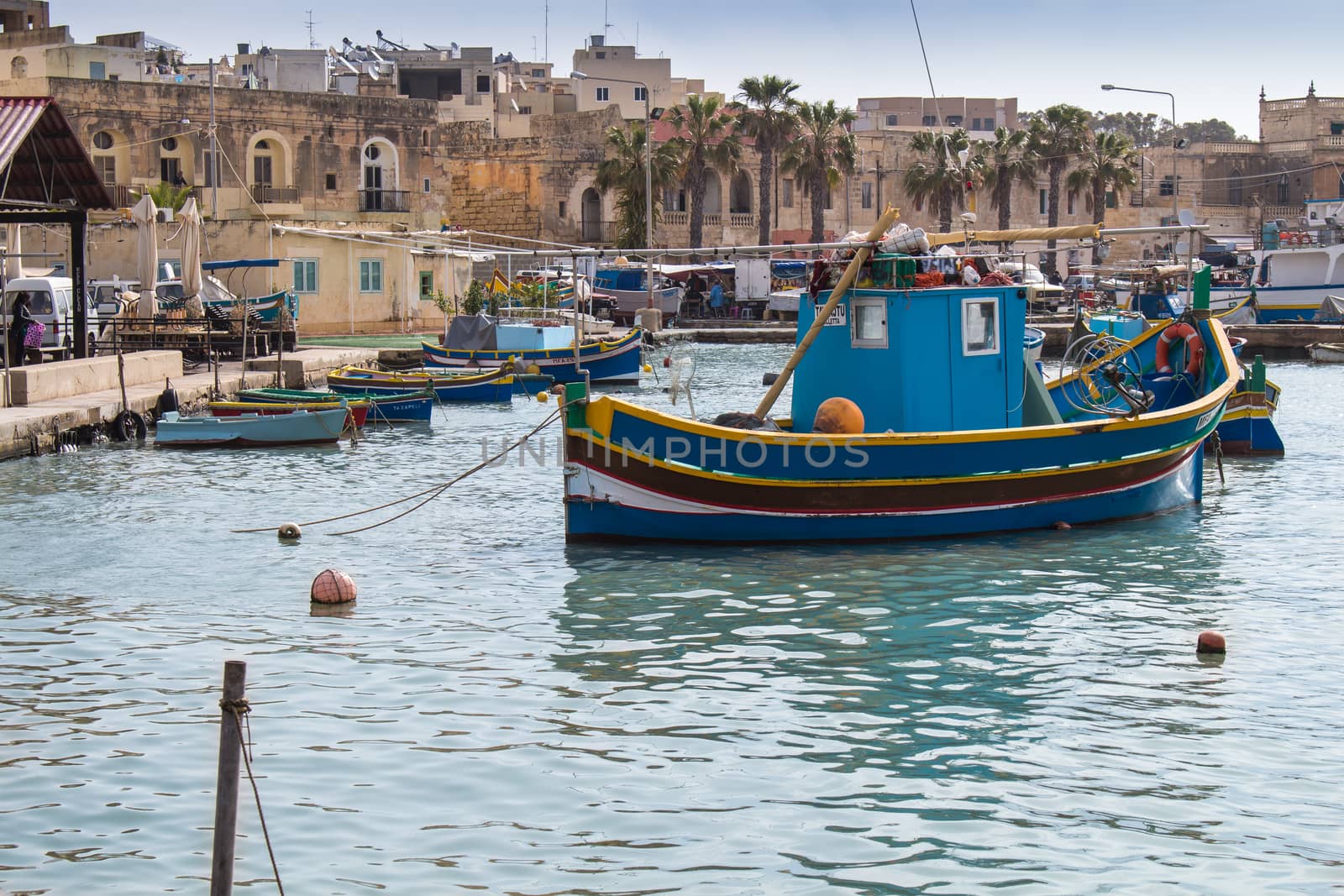 Water of the mediterranean sea, bay and port in the fishing village Marsaxlokk at the island Malta. Colorful traditional fishing boat.Houses in the background.