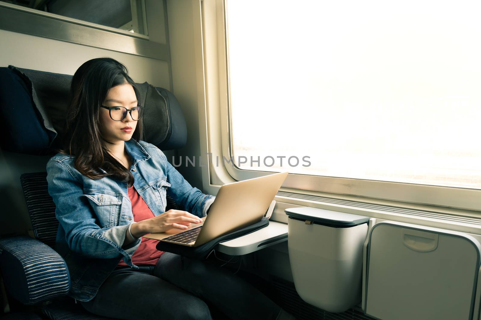 Asian woman work on laptop on train, business travel concept, warm light tone