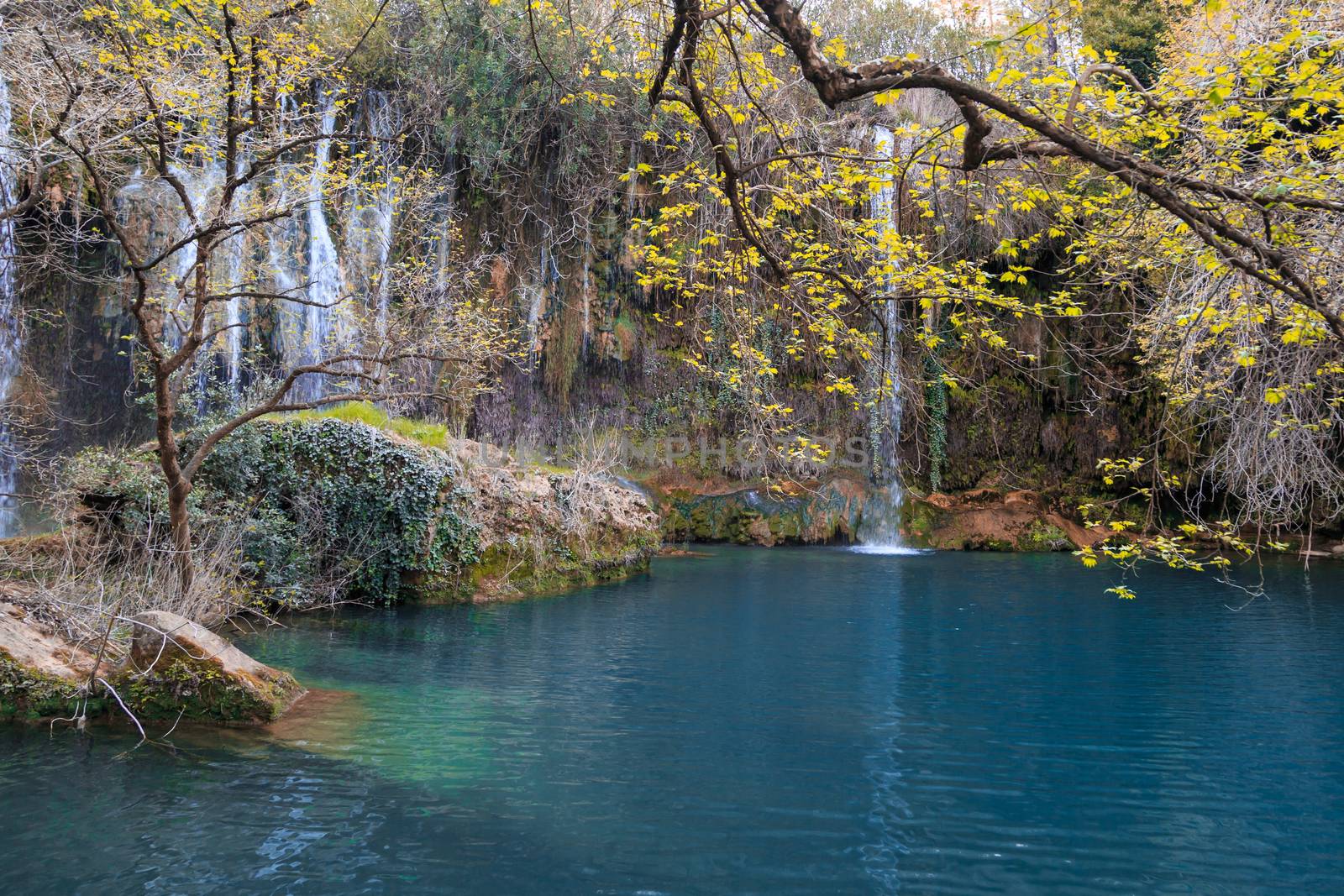 View of Kursunlu Waterfall in Antalya, flowing from high, with green trees and plants around.