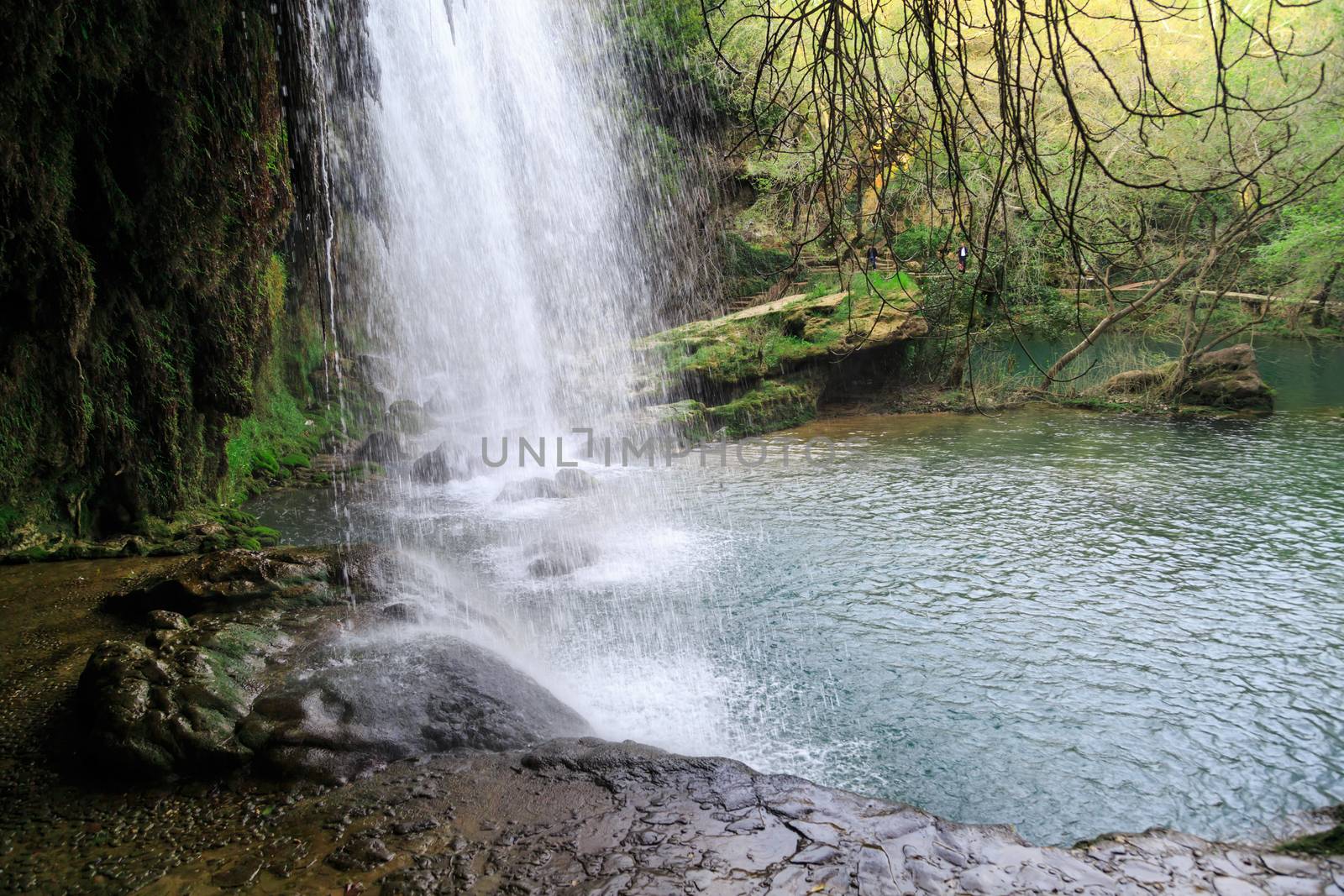 View of Kursunlu Waterfall in Antalya, flowing from high, with green trees and plants around.