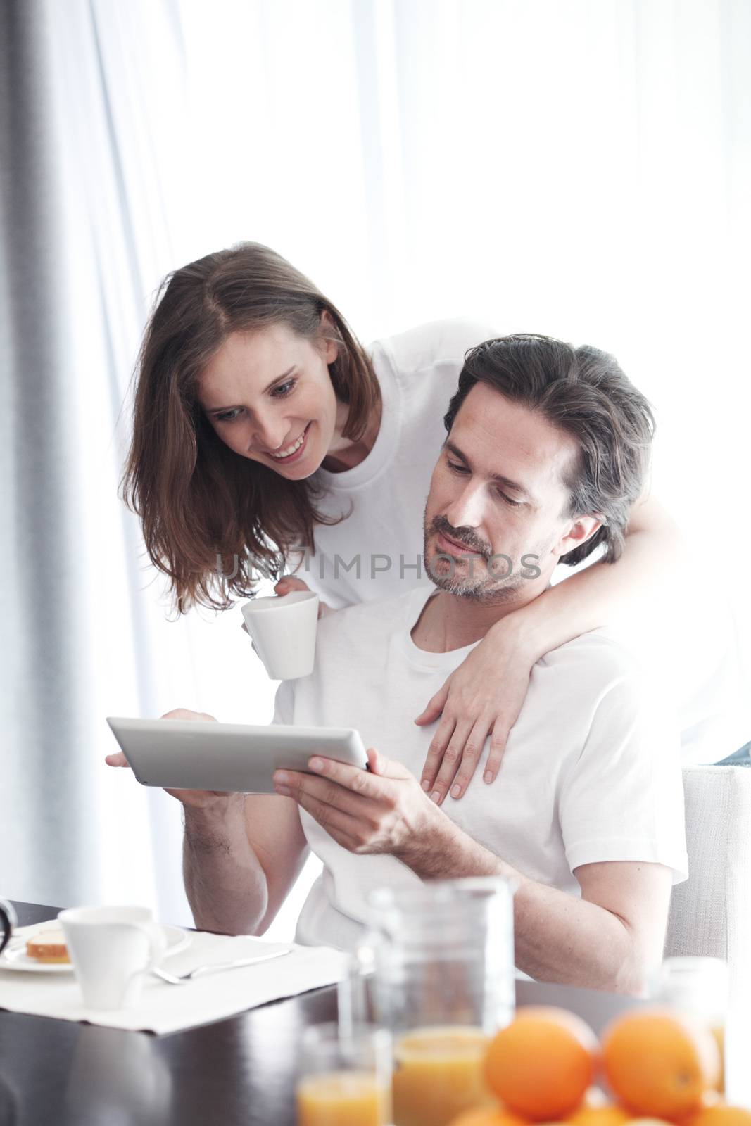 Couple having breakfast at home and using tablet