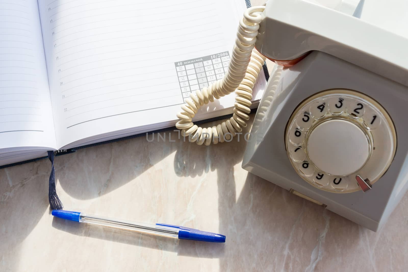 The photo depicts a landline phone with a notebook