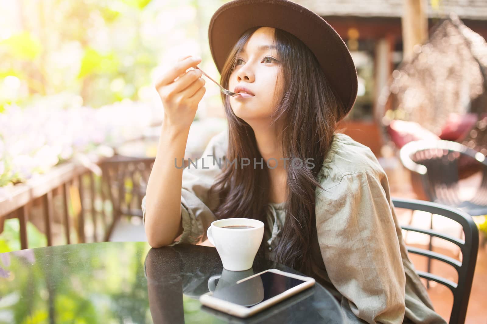 Woman drinking coffee in the garden, outdoor in sunlight light, enjoying her morning coffee.