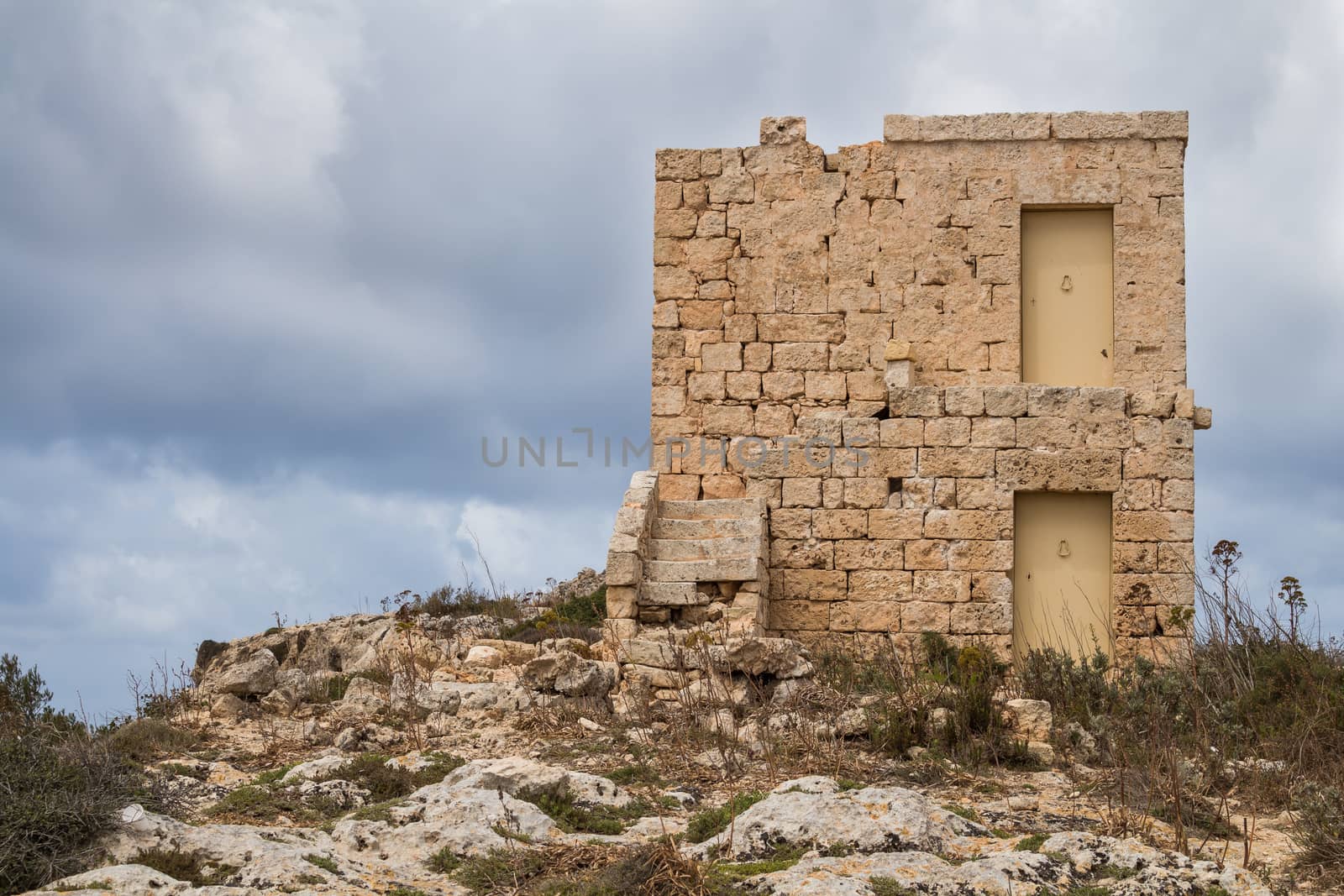 On the top of the hill at Dingli Cliffs, island Malta, an old house made of stones. Cloudy sky in the background.