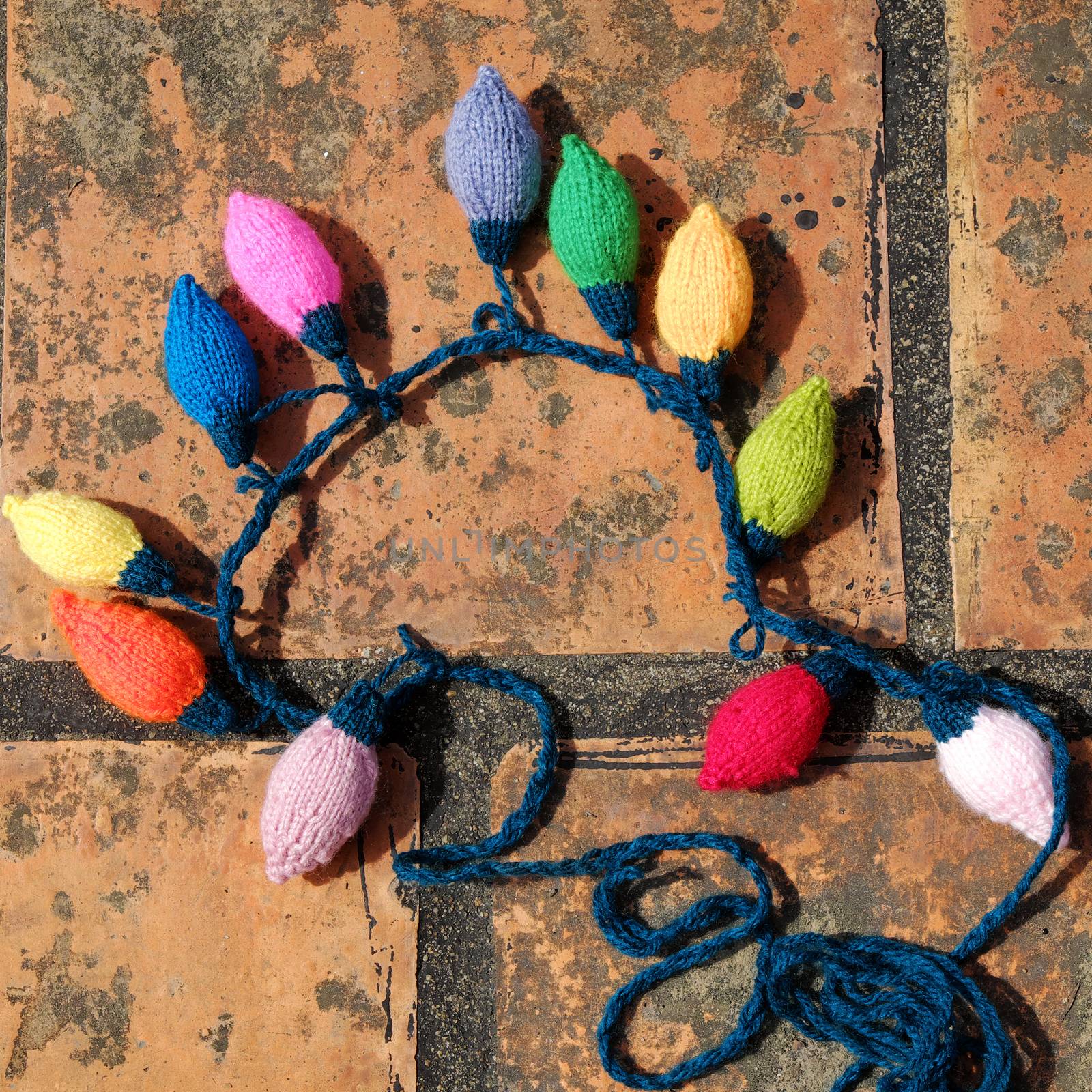 Group of colorful Xmas ornament for winter holiday, handmade product, knitted Christmas lights bulb on brick background