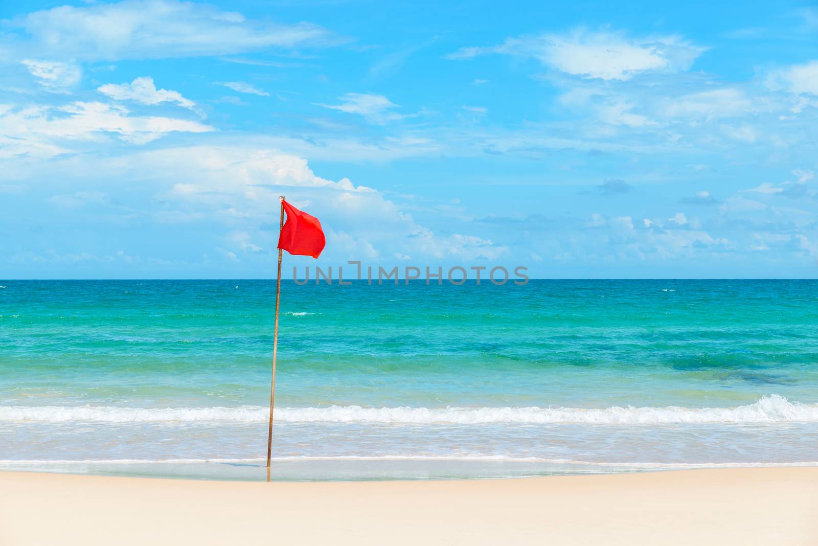 Red flag on tropical beach and azure sea