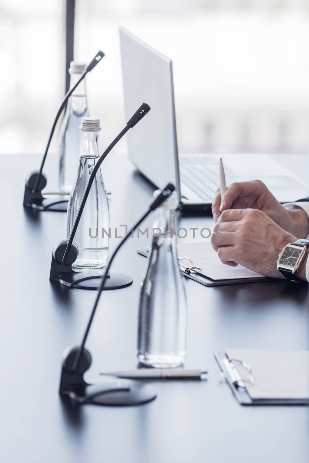 Microphones on table in conference room and business man hands 