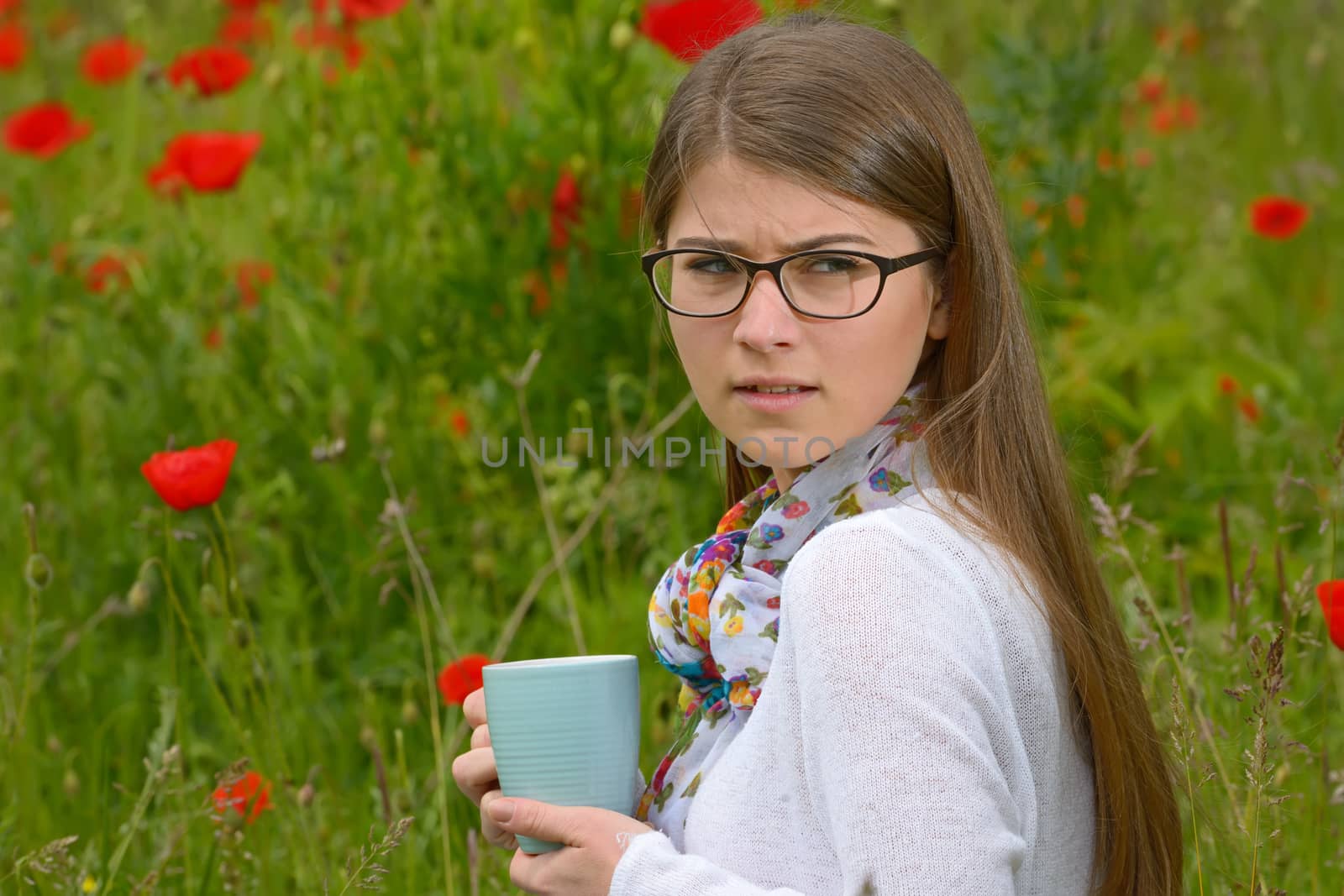 Teen girl drink cup of tea on poppy field