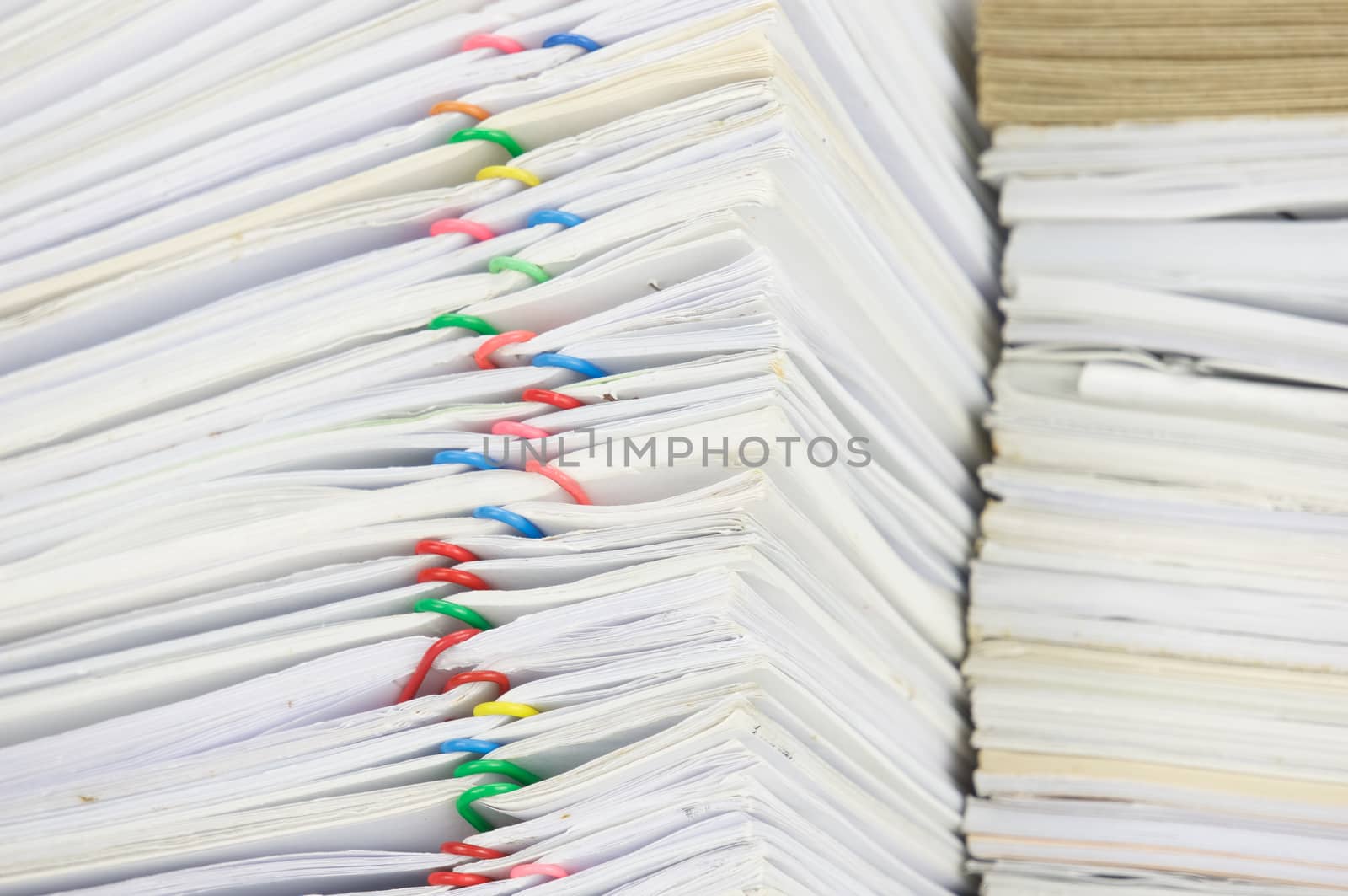 Close up overload paperwork of report and receipt with colorful paperclip have blur brown envelope on document.