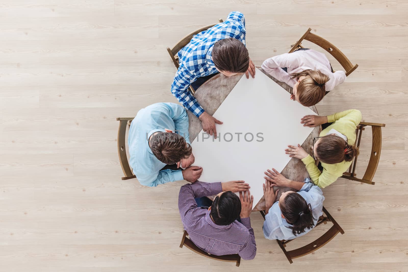 Businessteam working at meeting table, pointing at blank paper