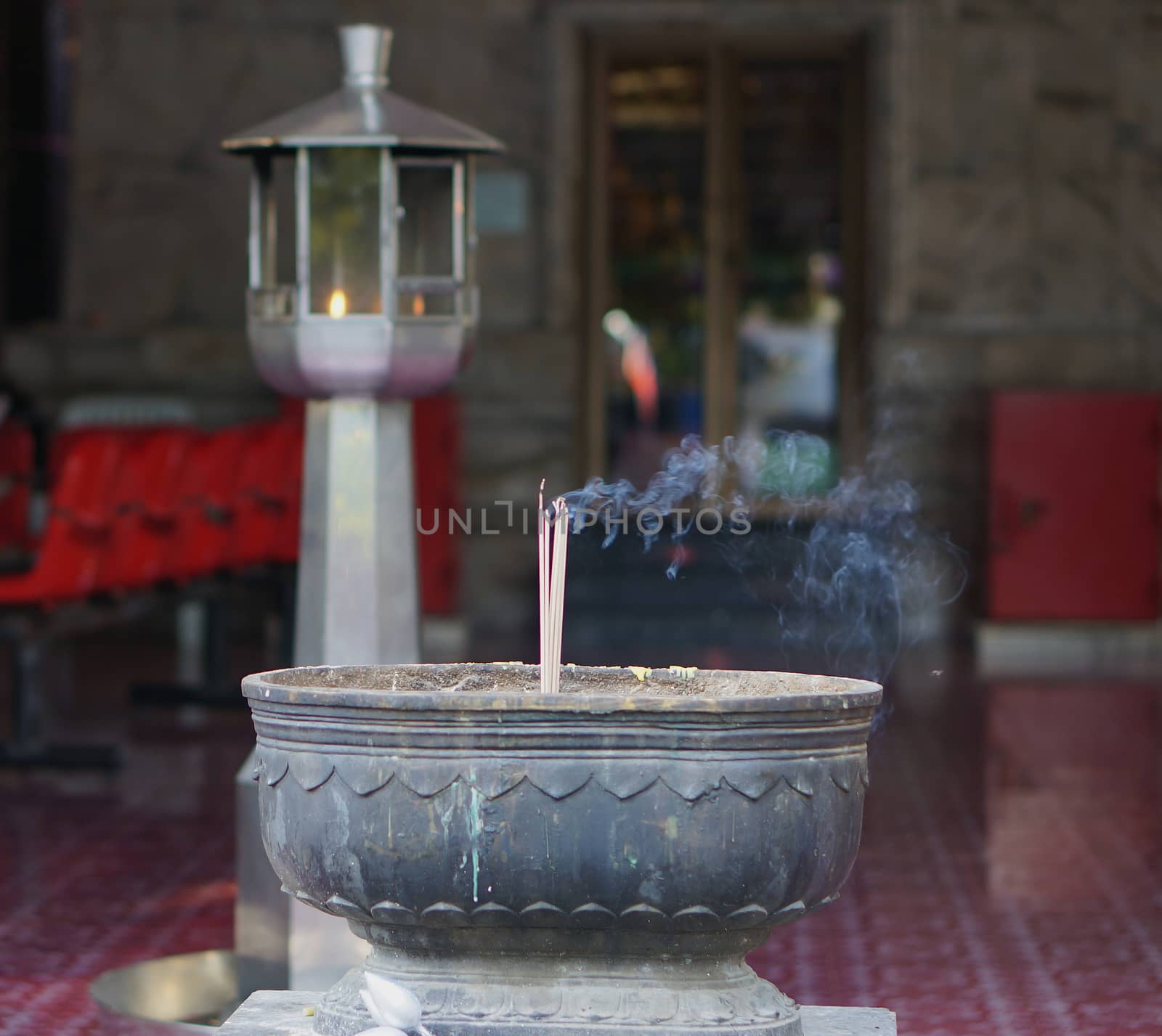 Incense sticks on joss stick pot are burning and smoke use for pay respect to the Buddha.