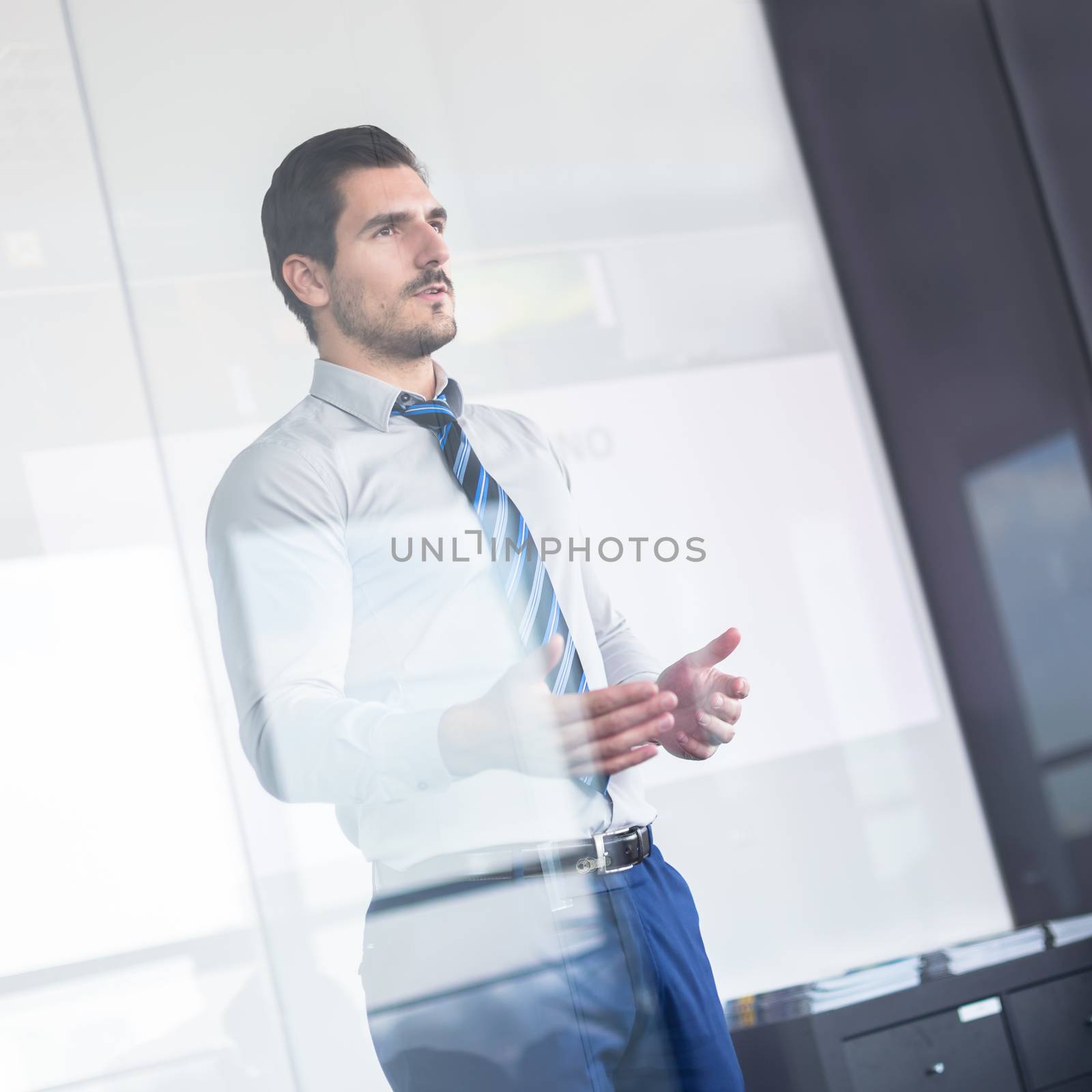 Business man making a presentation in front of whiteboard. View through glass.