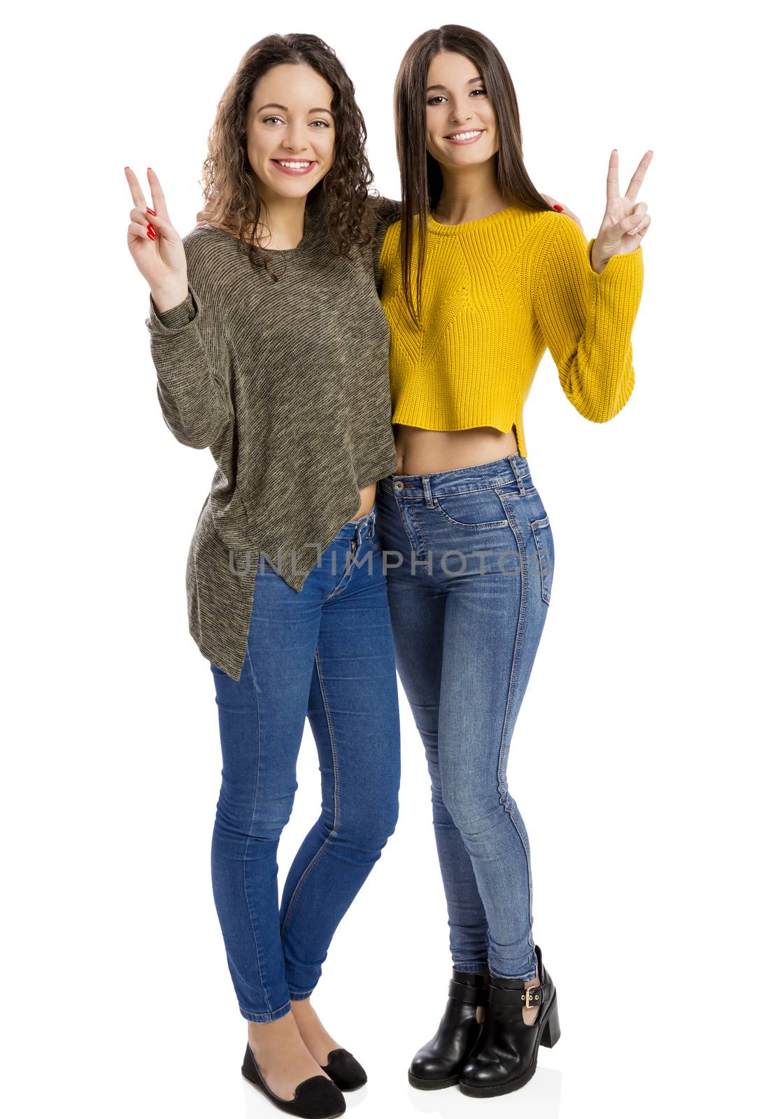 Studio portrait of two beautiful girls with arms open
