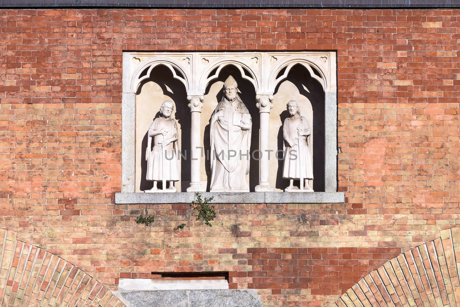 In the picture three statues, located in the center the statue of Saint Ambrose, Milan, Italy.