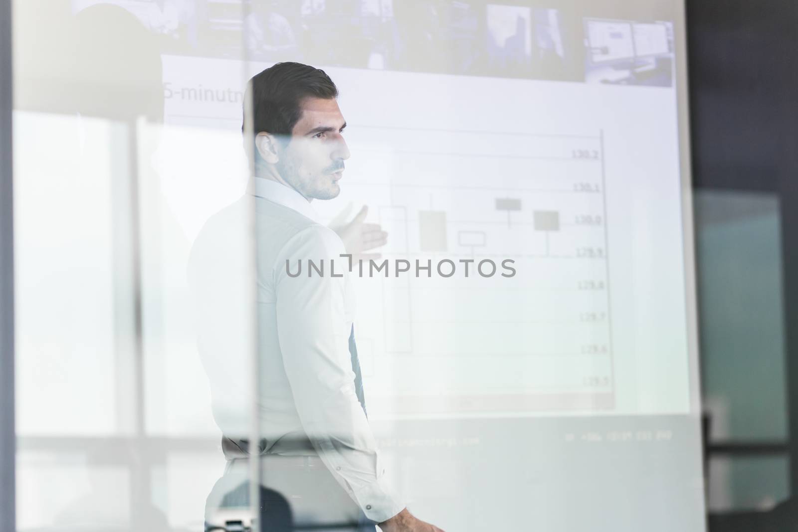Business man making a presentation in front of whiteboard. View through glass.