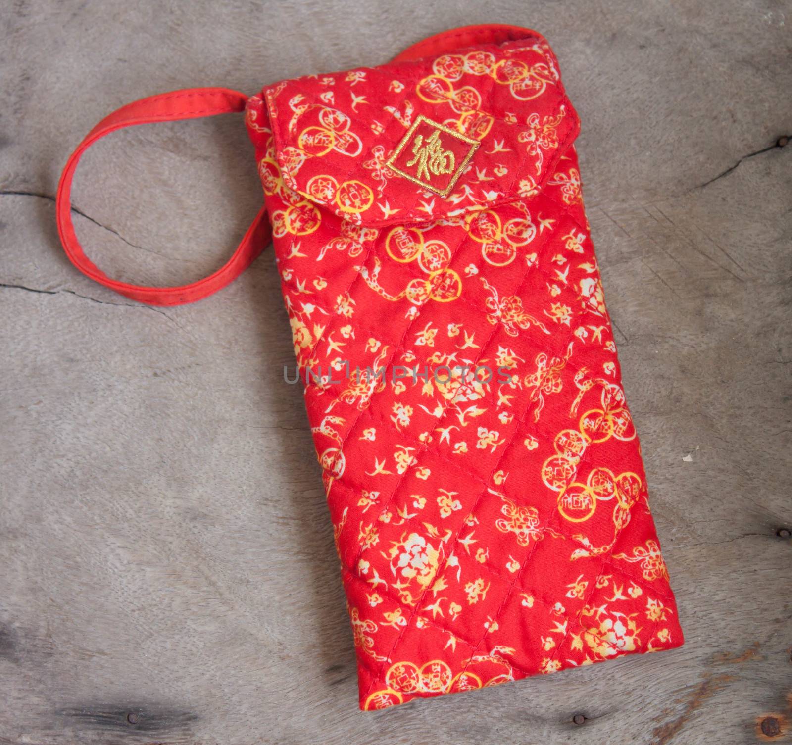 Red envelope with red cloth is soft in the background.
Wood