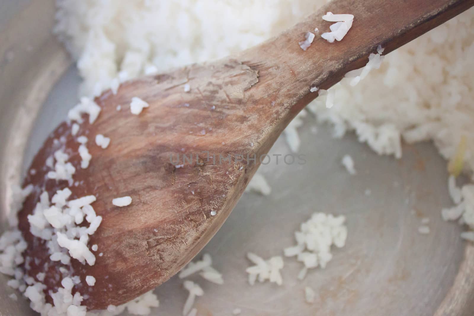 Wooden spoon with rice in a rice cooker.