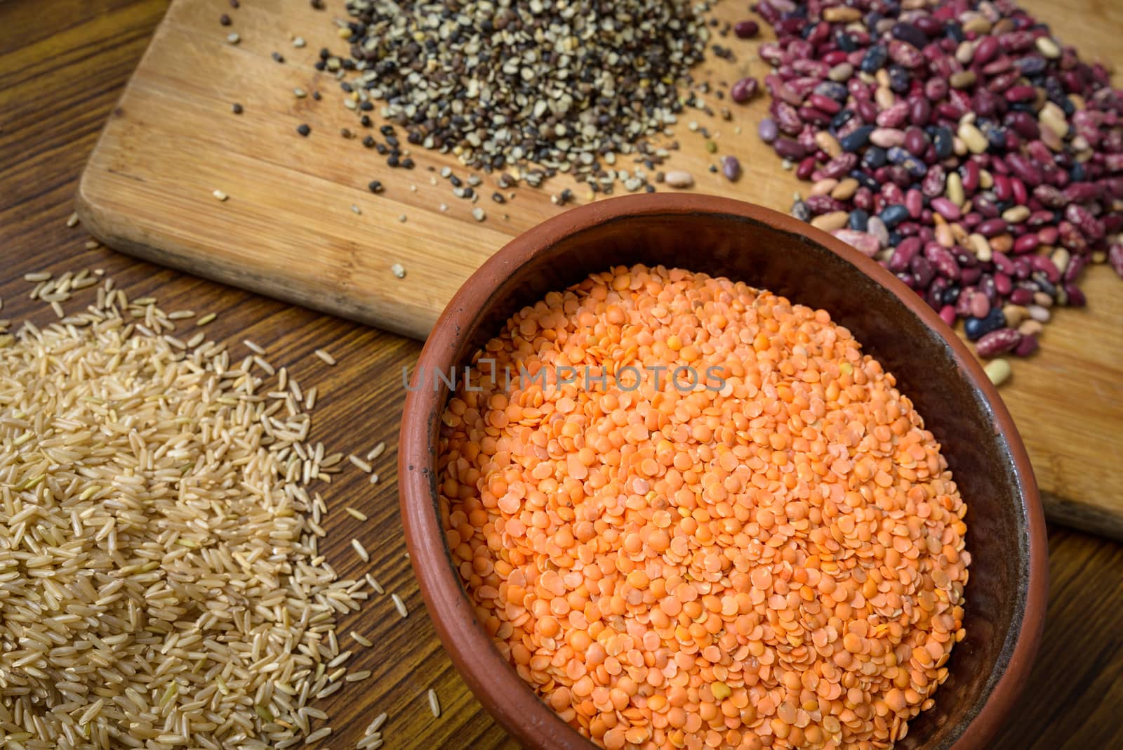 Lentils, red beans and brown rice on a wooden table and board