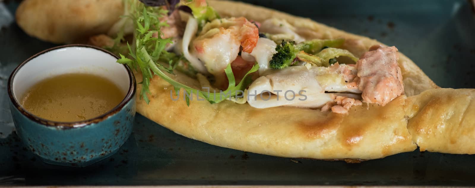 Georgian dish khachapuri with seafood and fresh vegetables close-up