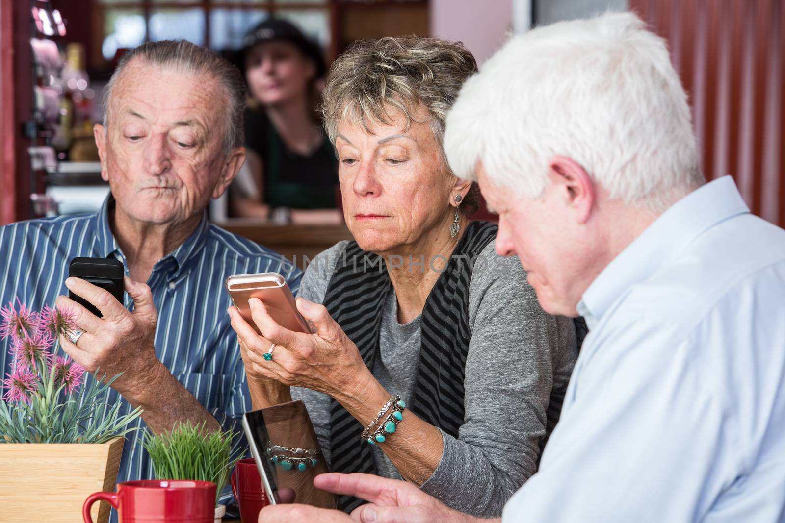 Mature friends in a coffee house distracted by their devices