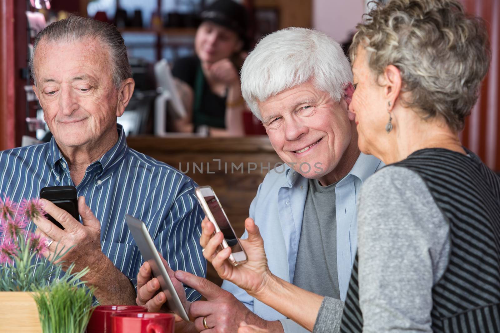 Happy mature friends using wifi in a coffeehouse