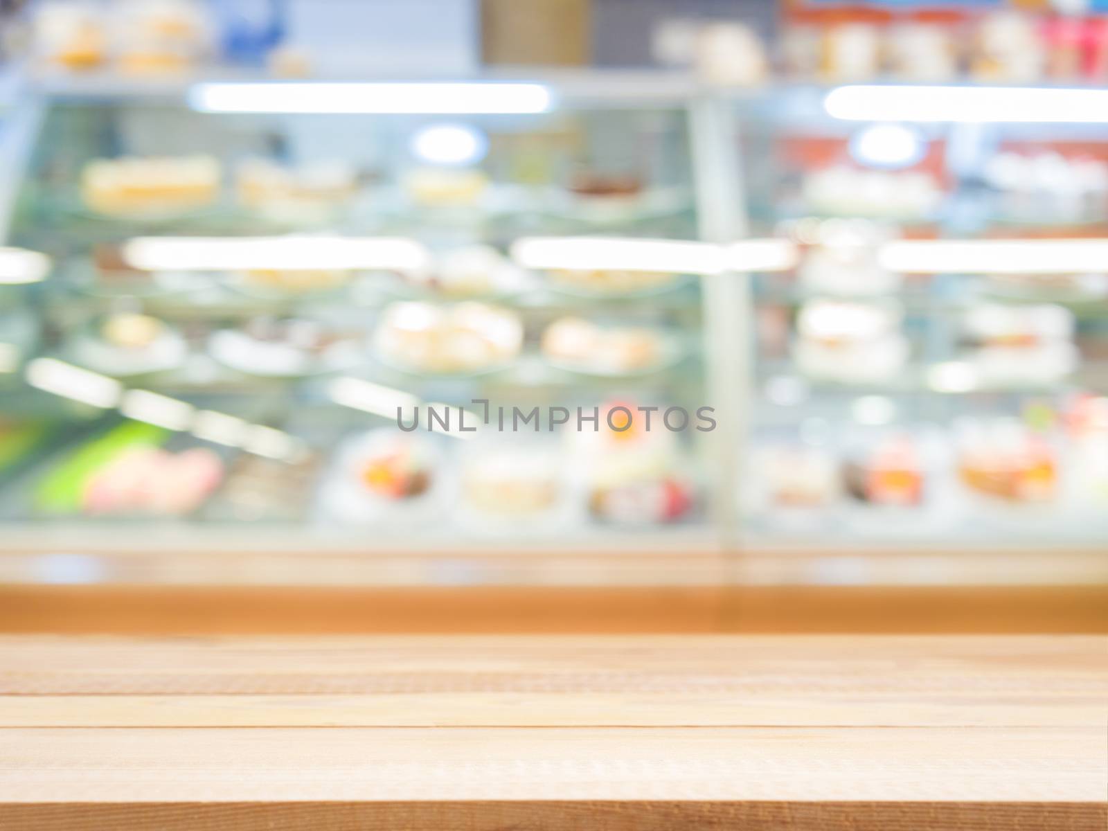 Wooden empty table in front of blurred bakery shop by fascinadora