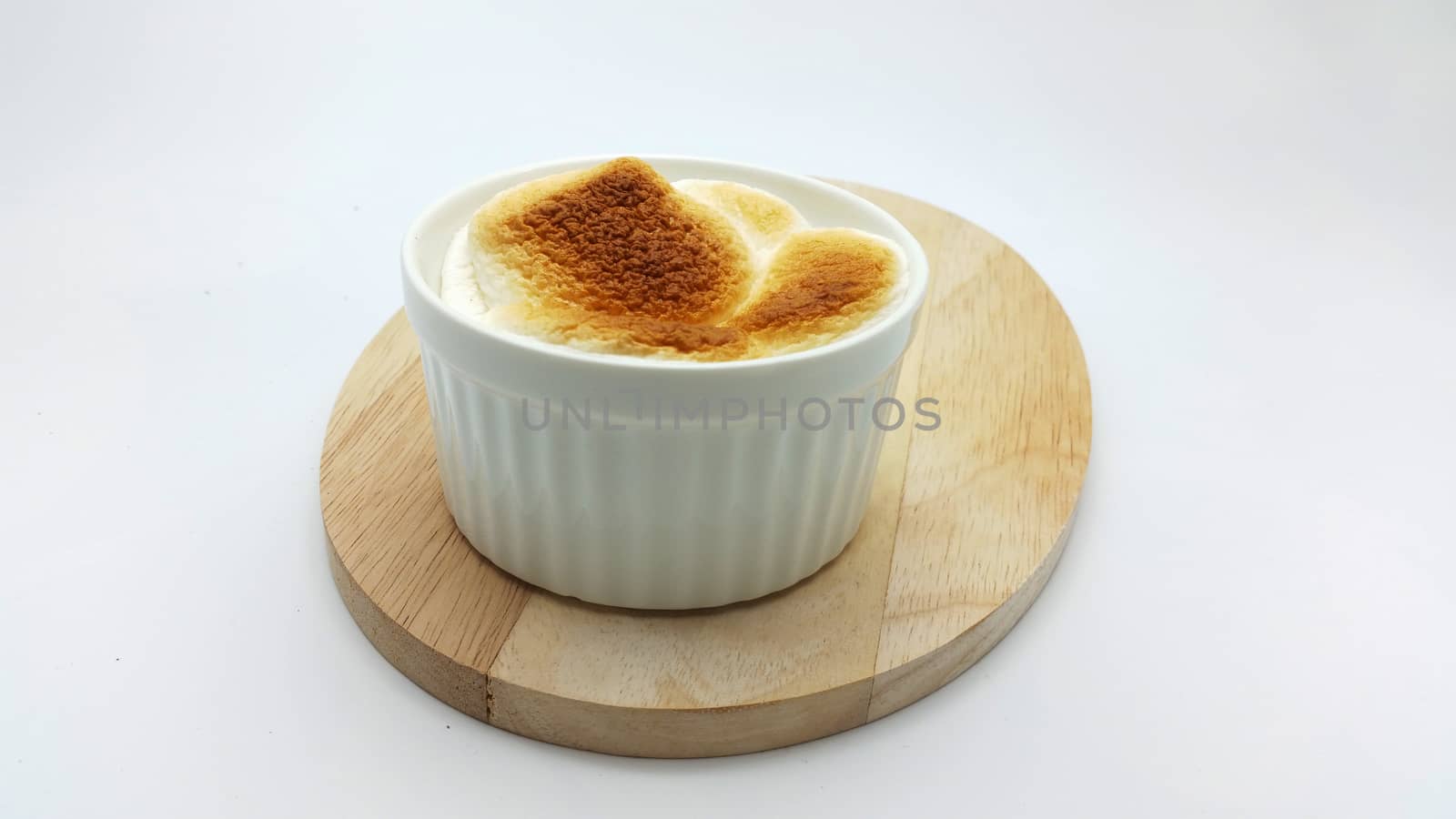 S'More dip (baked marshmellow and chocolate) in a ceramic cup on white background