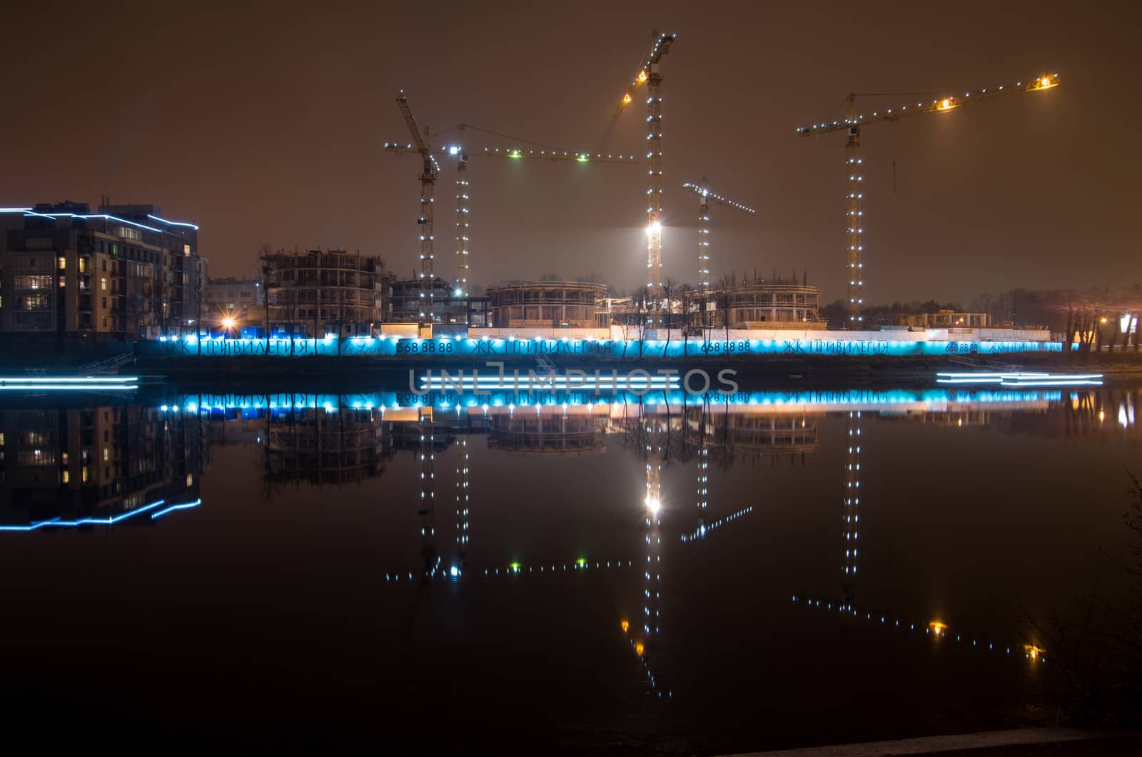 Tower cranes night view from the embankment of Admiral Lazarev, building in St. Petersburg