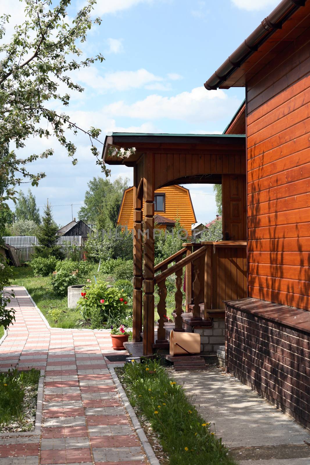 Wooden country house with nice porch against garden background