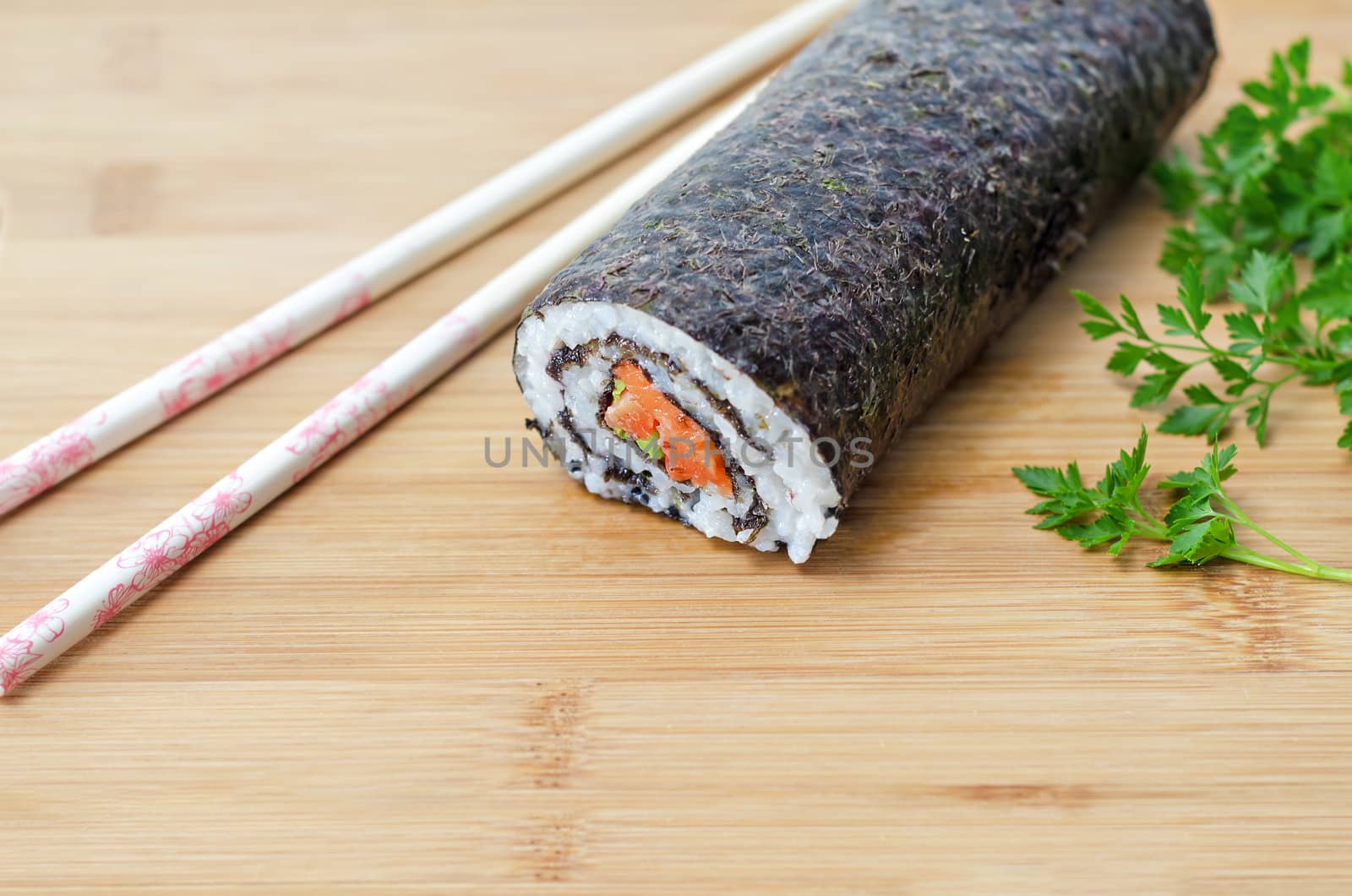 Rolls with salmon, a large piece, parsley and chopsticks on wooden background.