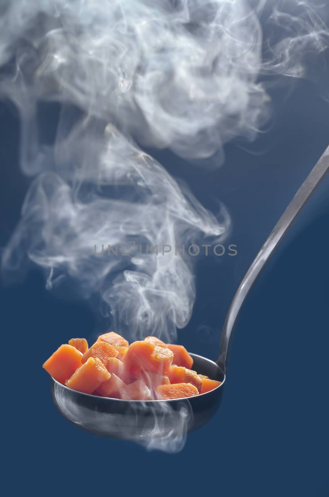 Hot boiled carrots in a bucket, diced. Blue background, from hot vegetables, steam rises.