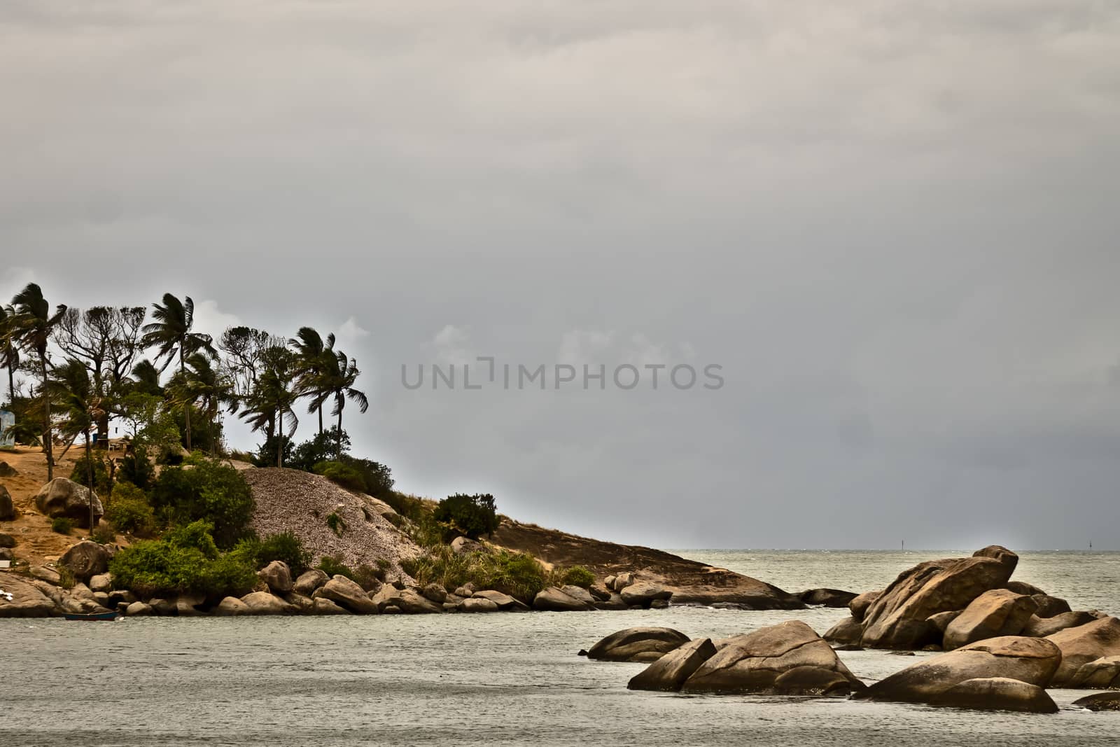 view of island with palm trees and rocks against cloudy sky