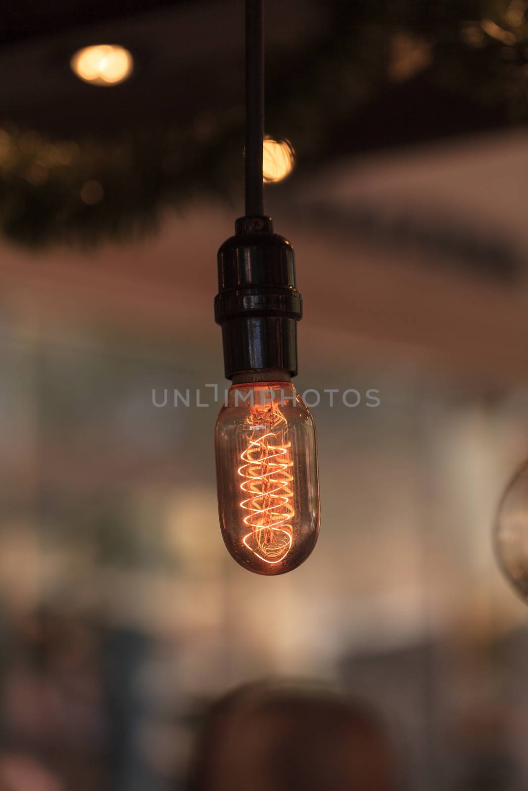 Ornamental light bulb lit up and hanging from the ceiling with a modern kitchen in the background, representing a rustic concept of success.