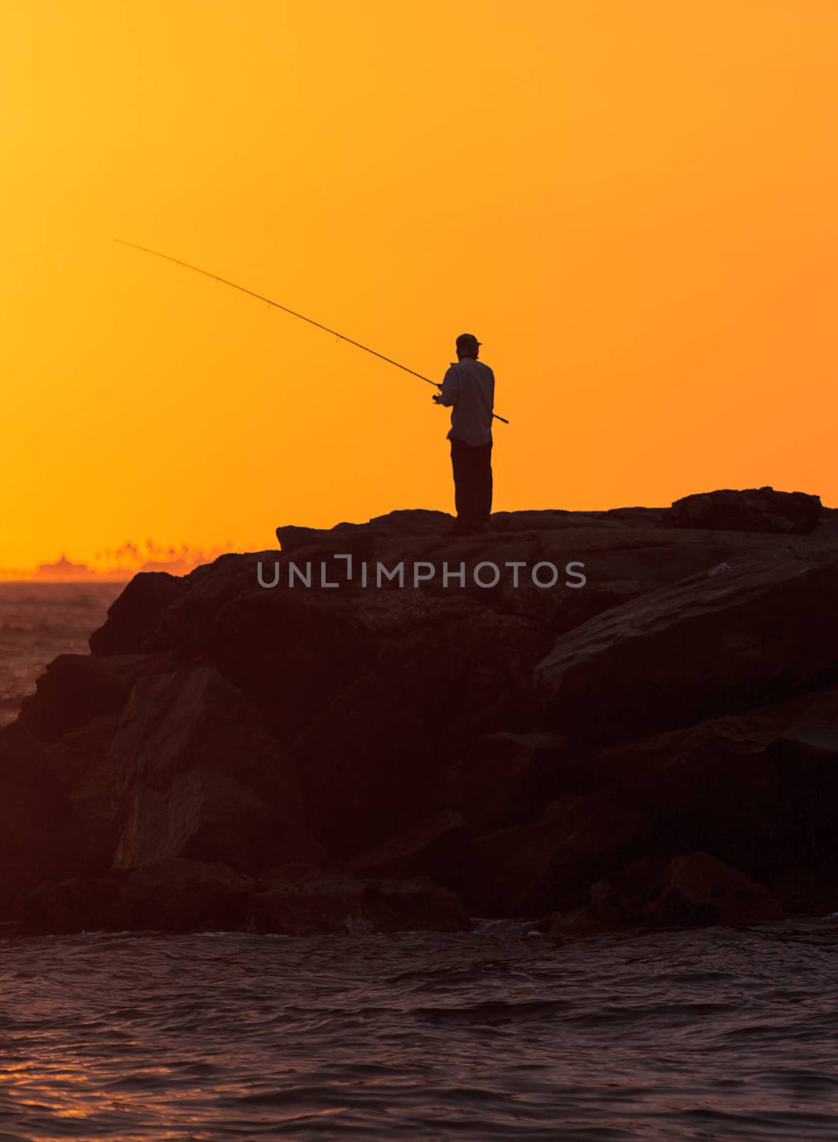 Silhouette of Men fishing on the pier off Balboa Island, Newport Beach at sunset in Southern California