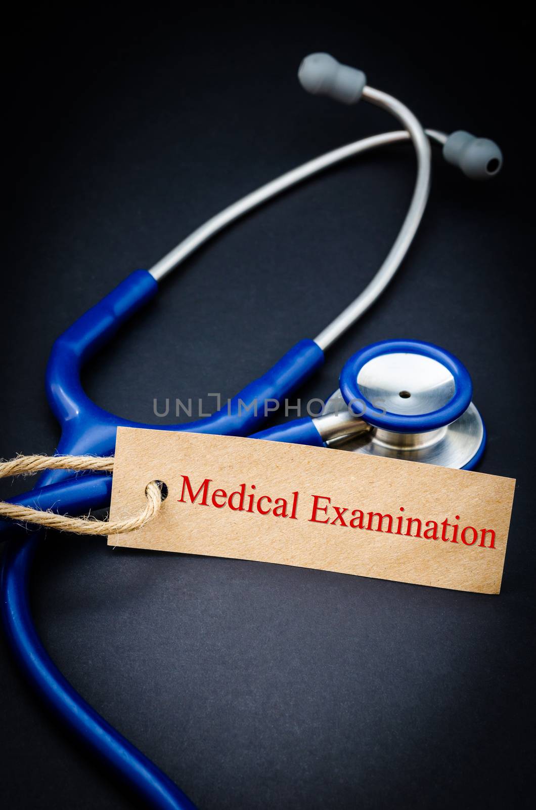 Medical examination in paper tag with stethoscope on black background - health concept. Medical conceptual