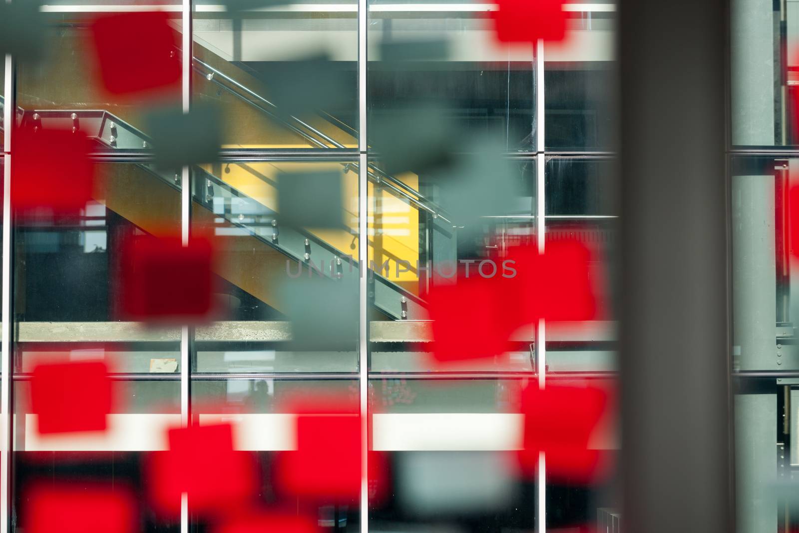 Office window used to ideas board with defocused red sticky note papers stuck to the inside looking through to next building.