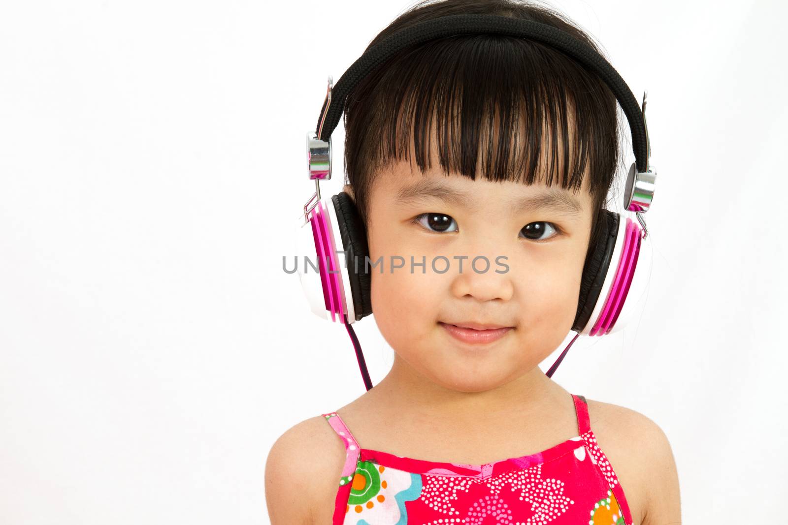 Chinese little girl on headphones smile with plain white isolated background.