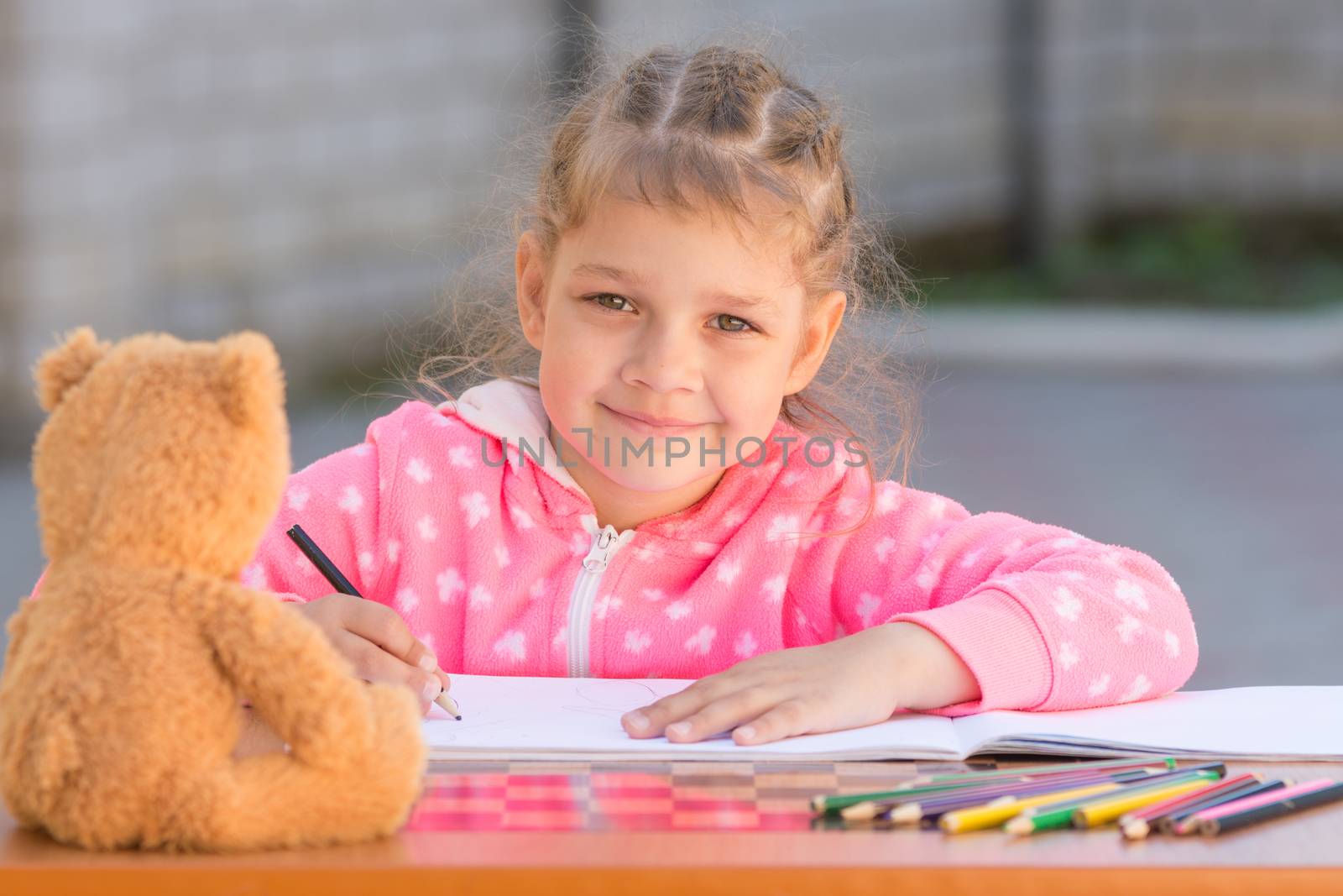 Girl draws with crayons and smile, he looked into the frame
