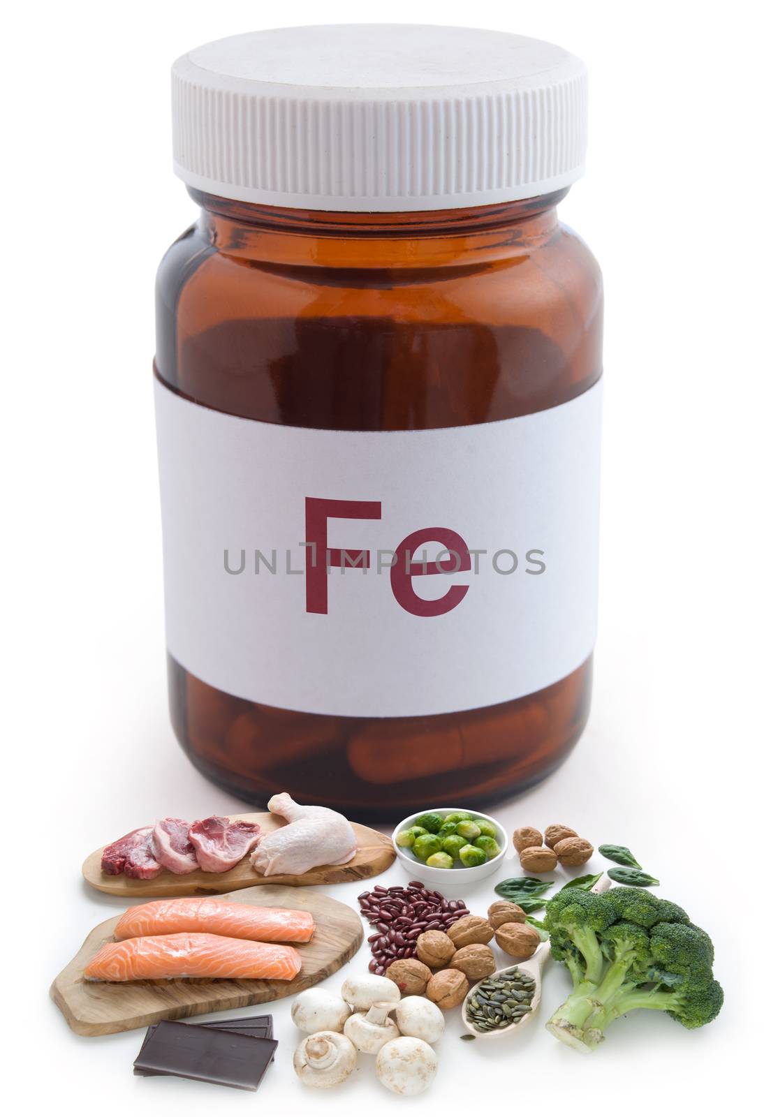 Iron rich foods next to a pill jar over a white background