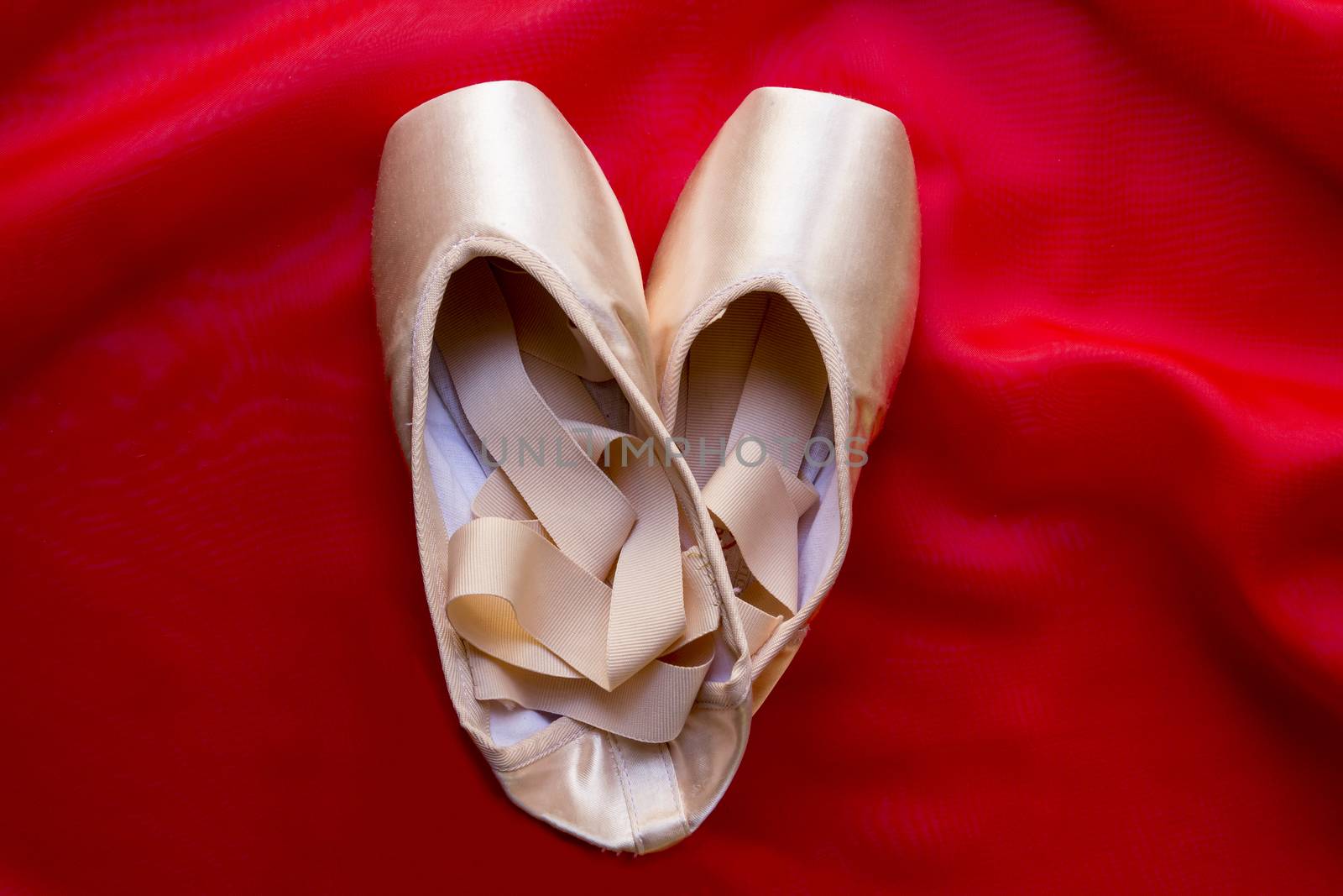 Ballet shoes on delicate red silk background