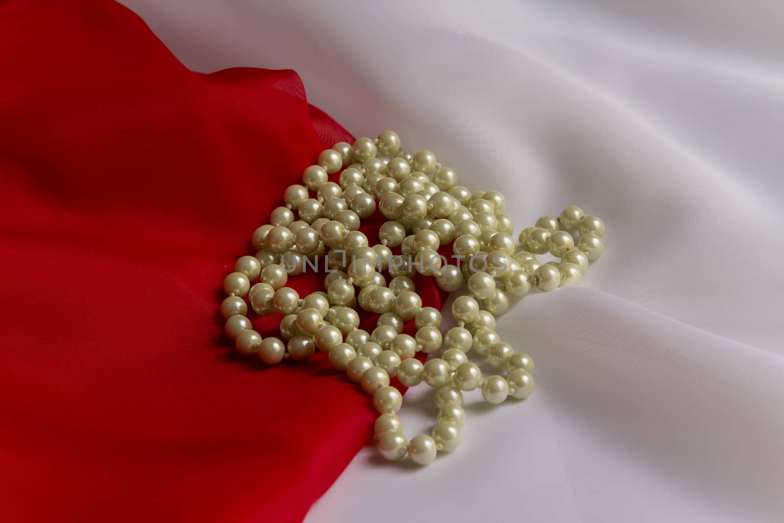 Pearl necklace on a background of delicate white and red silk