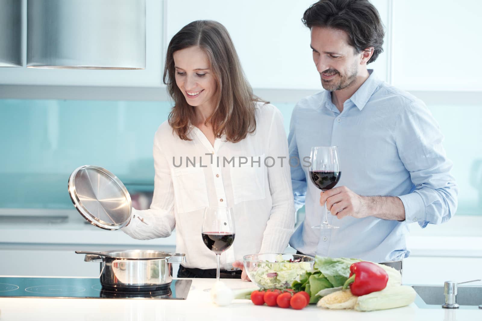 Portrait of a couple having a glass of red wine while cooking dinner