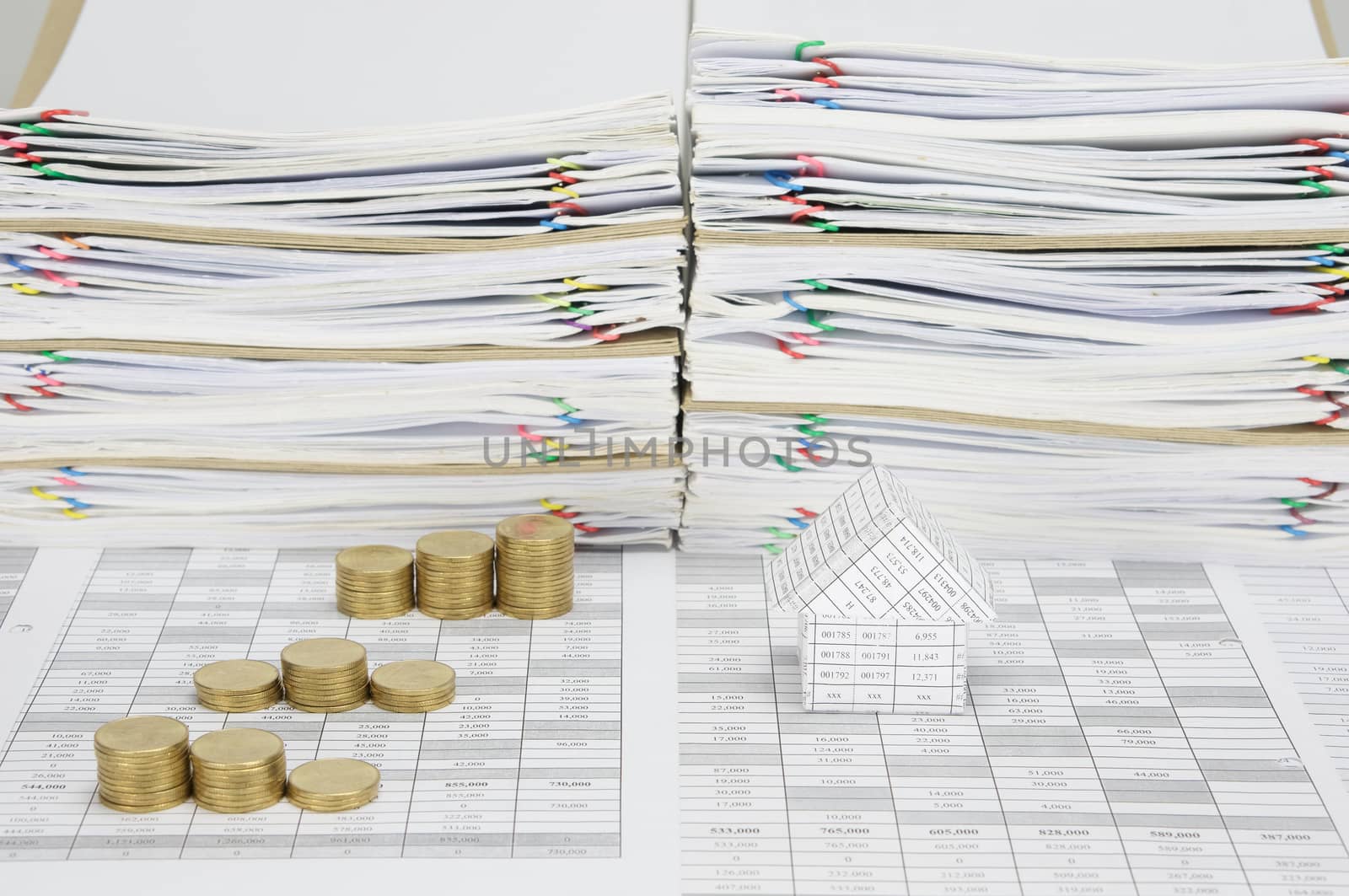 House and step pile of gold coins on finance account have overload of paperwork with colorful paperclip and envelope as background.