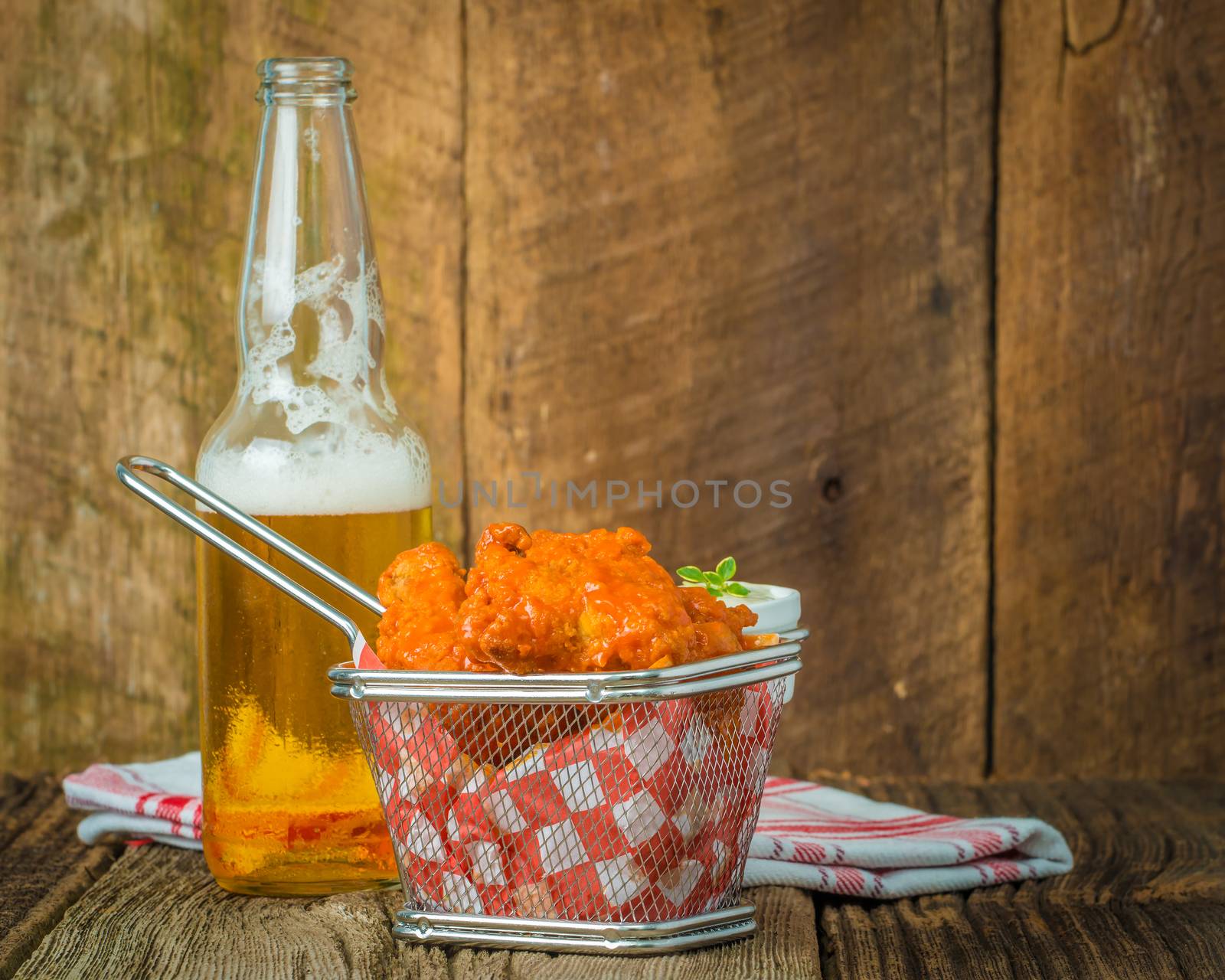 Spicy buffalo style wings in a basket served with cold beer.