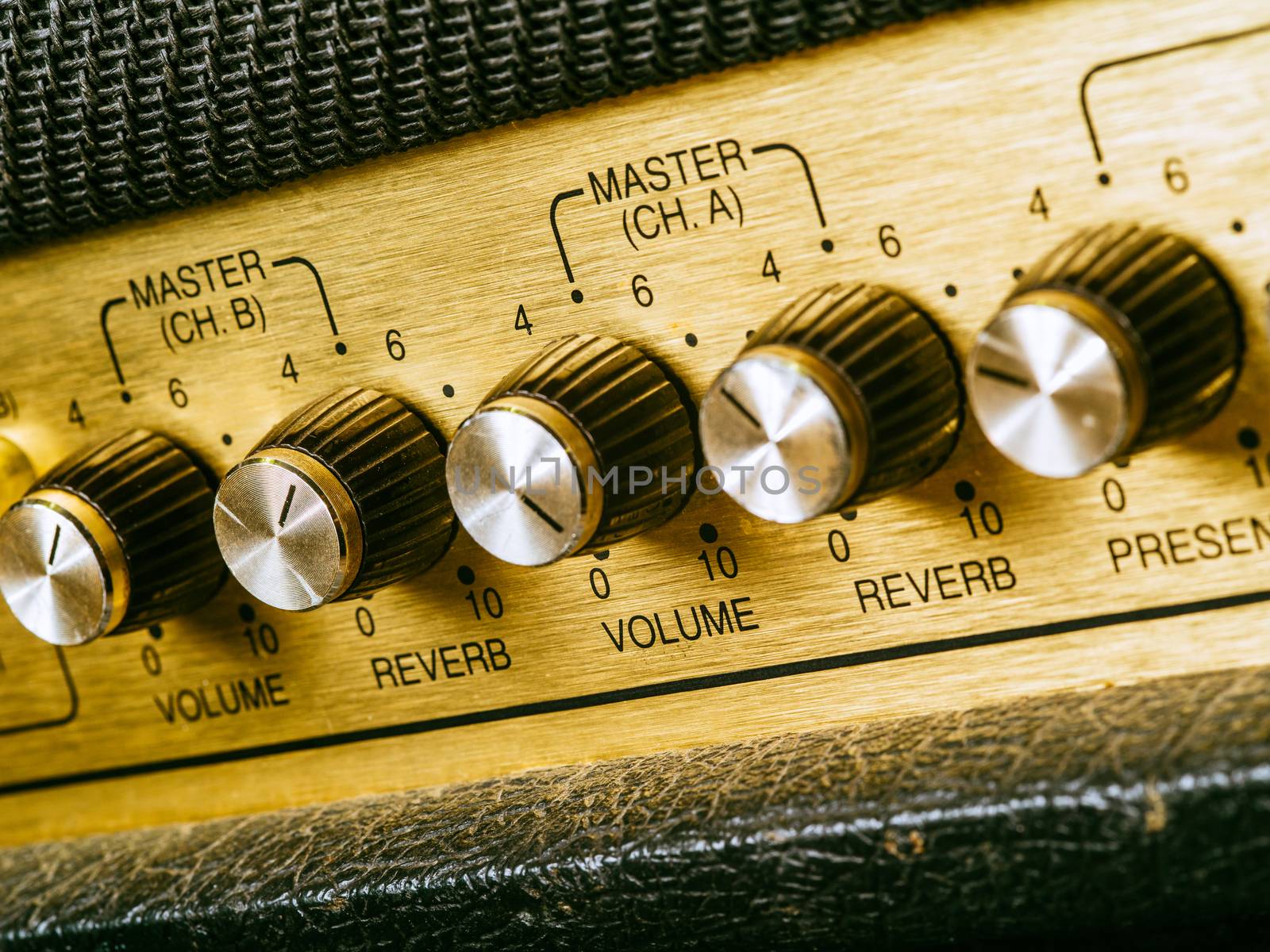Macro photo of a vintage electric guitar amplifier focusing on the volume knob which is set at ten.