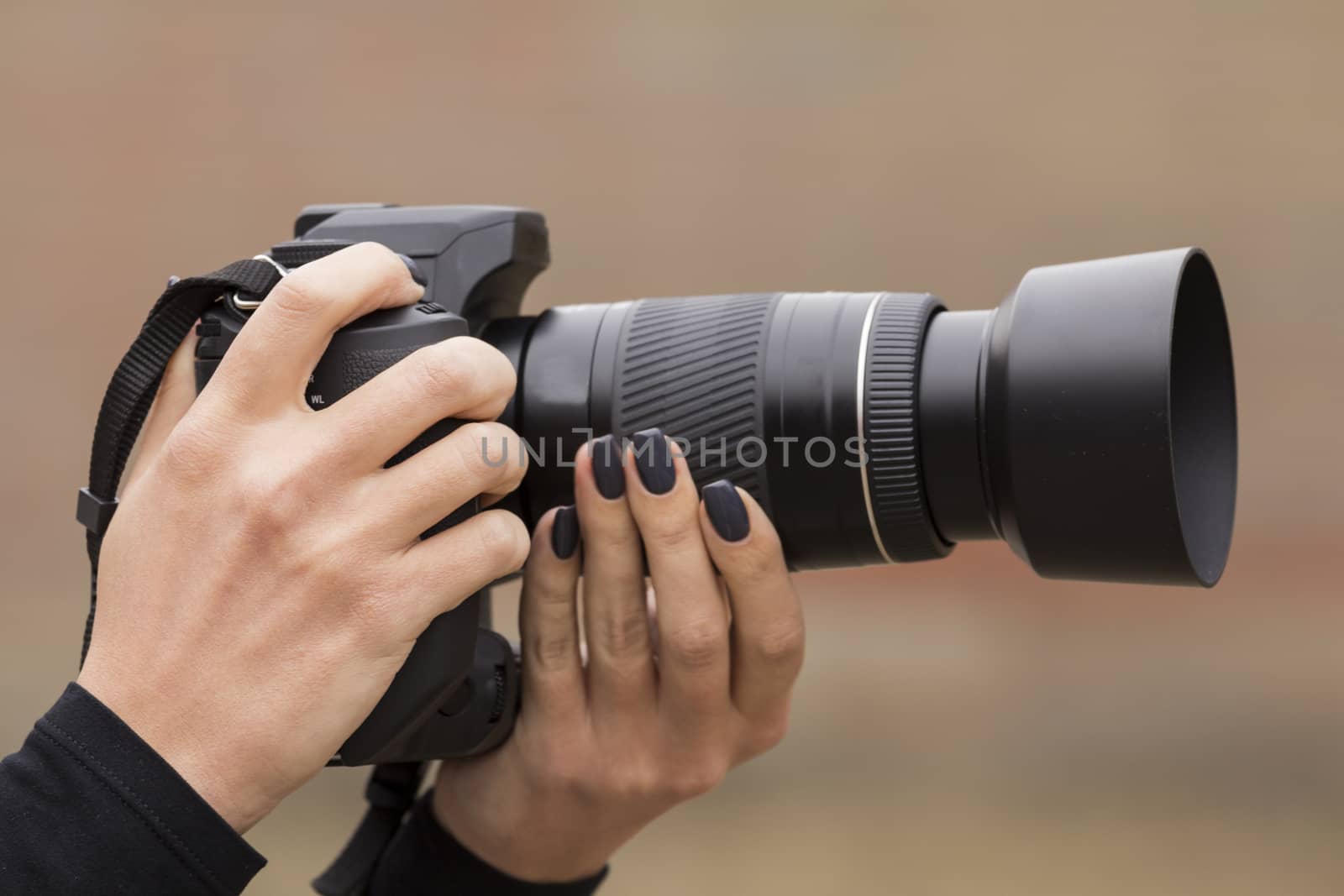 girl with beautiful manicure photographs on single-lens reflex camera